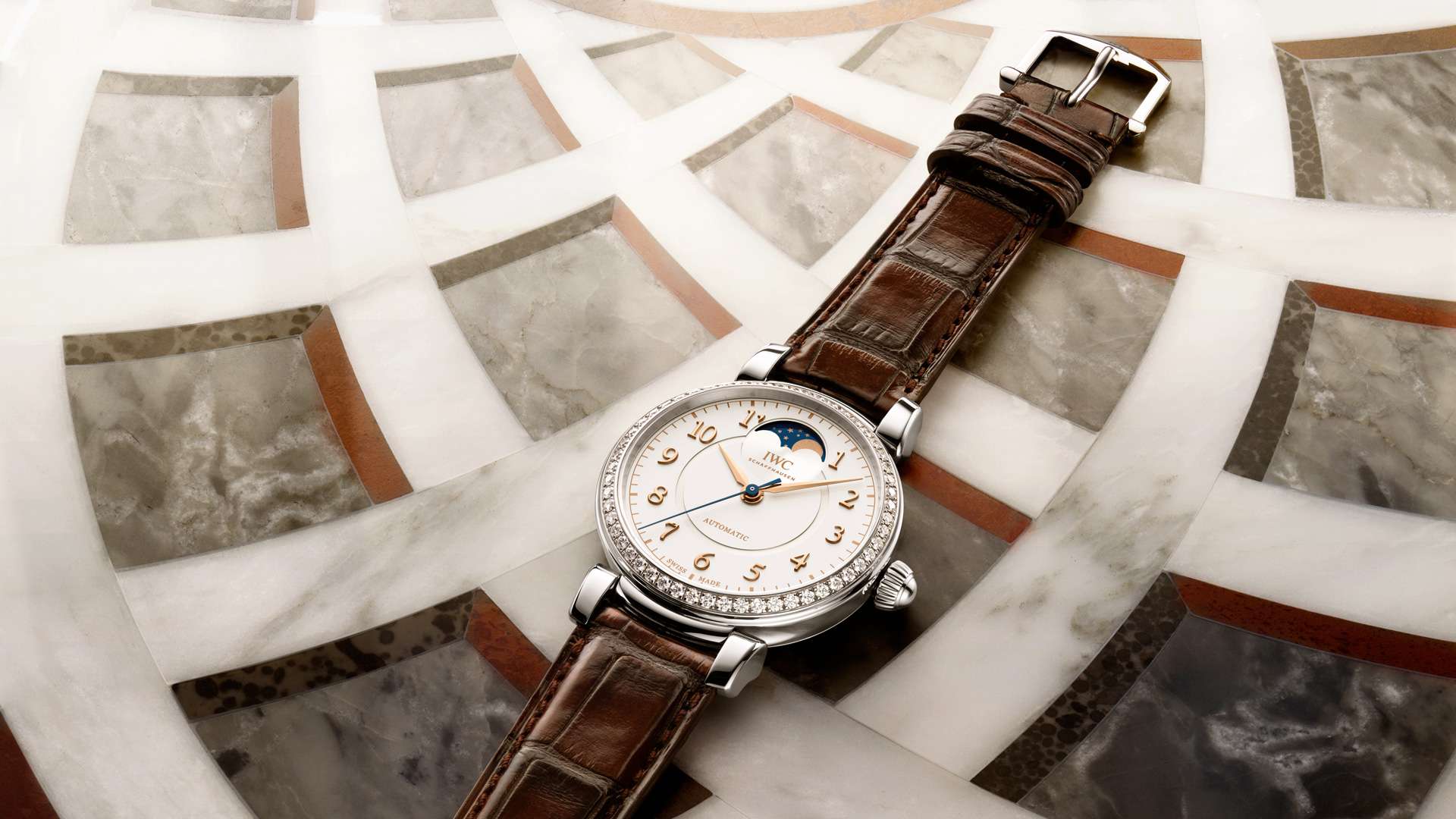 A IWC Schaffhausen Da Vinci with moon phase, diamond-set bezel and brown leather strap on a marble surface