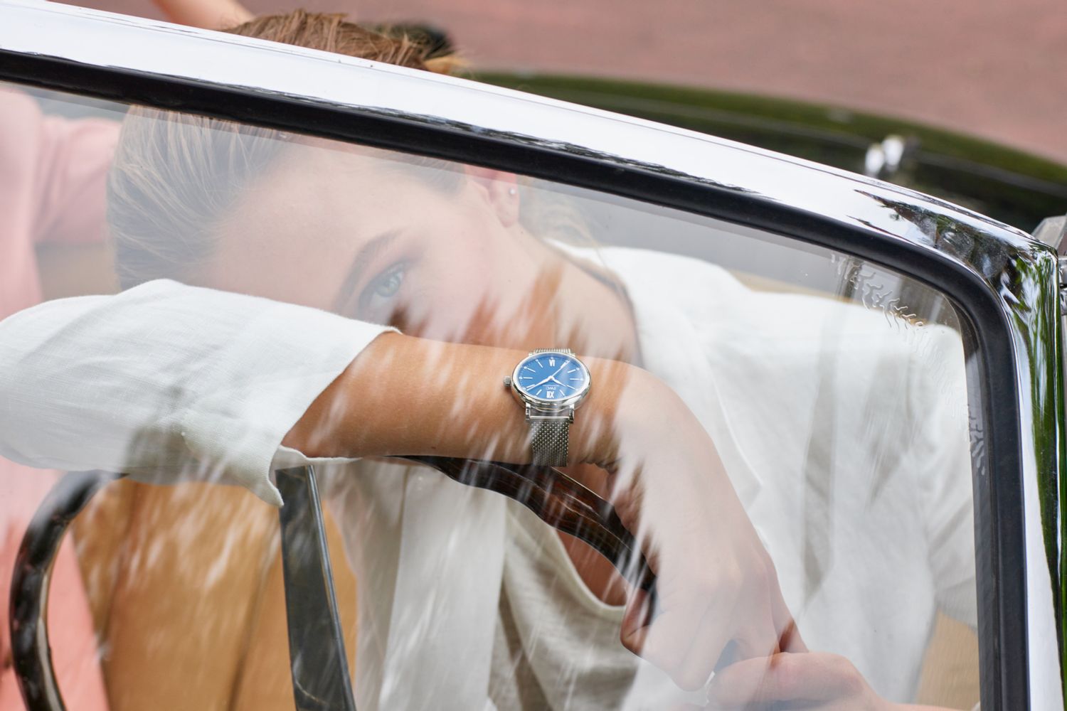 A woman sits in a car wearing an IWC Schaffhausen Portofino with a dark blue dial and a fine stainless steel bracelet.