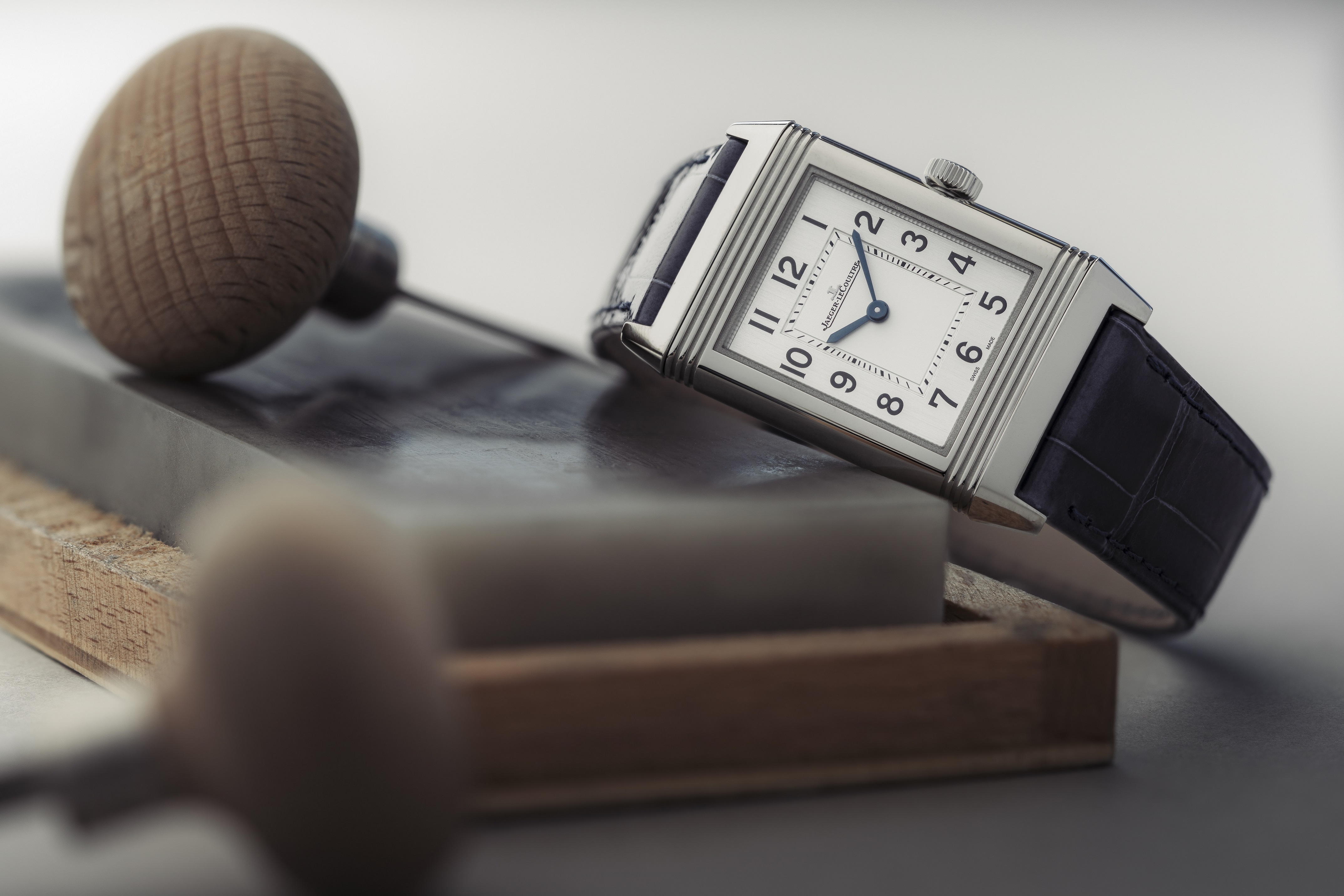 Jaeger-LeCoultre Reverso Classic lies at an angle on an engraving block, out of focus, with engraving tools in front of it.