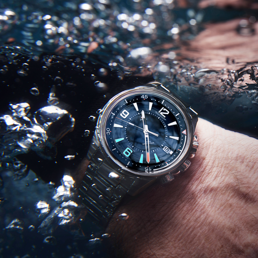 Jaeger-LeCoultre Polaris with blue dial is submerged in water on the wrist, with air bubbles rising all around.