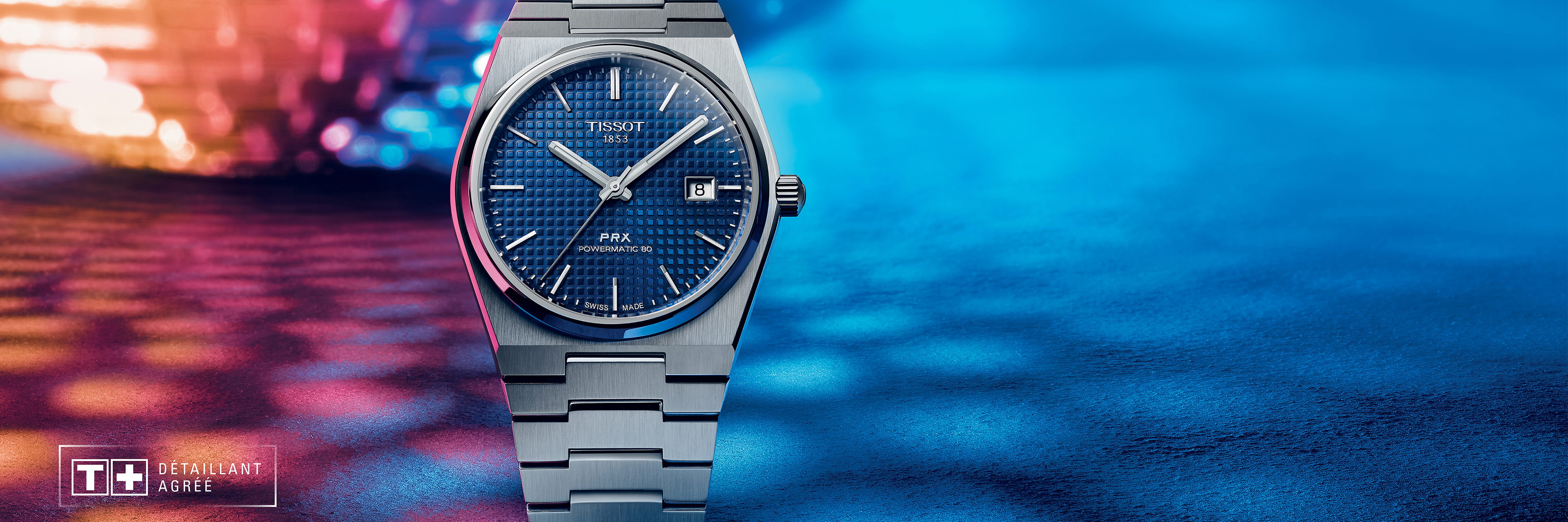 A Tissot PRX with blue dial and stainless steel bracelet against a colorful background