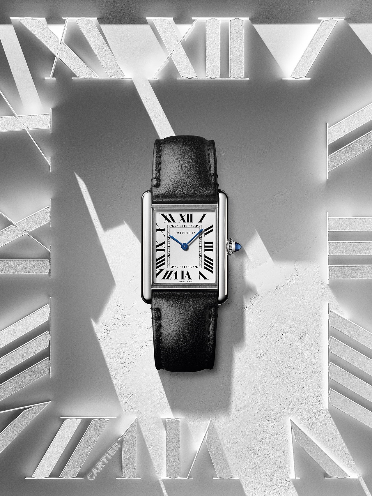 Cartier Tank with rectangular case, Roman numerals and blue hands, set against a light background with shadow play.