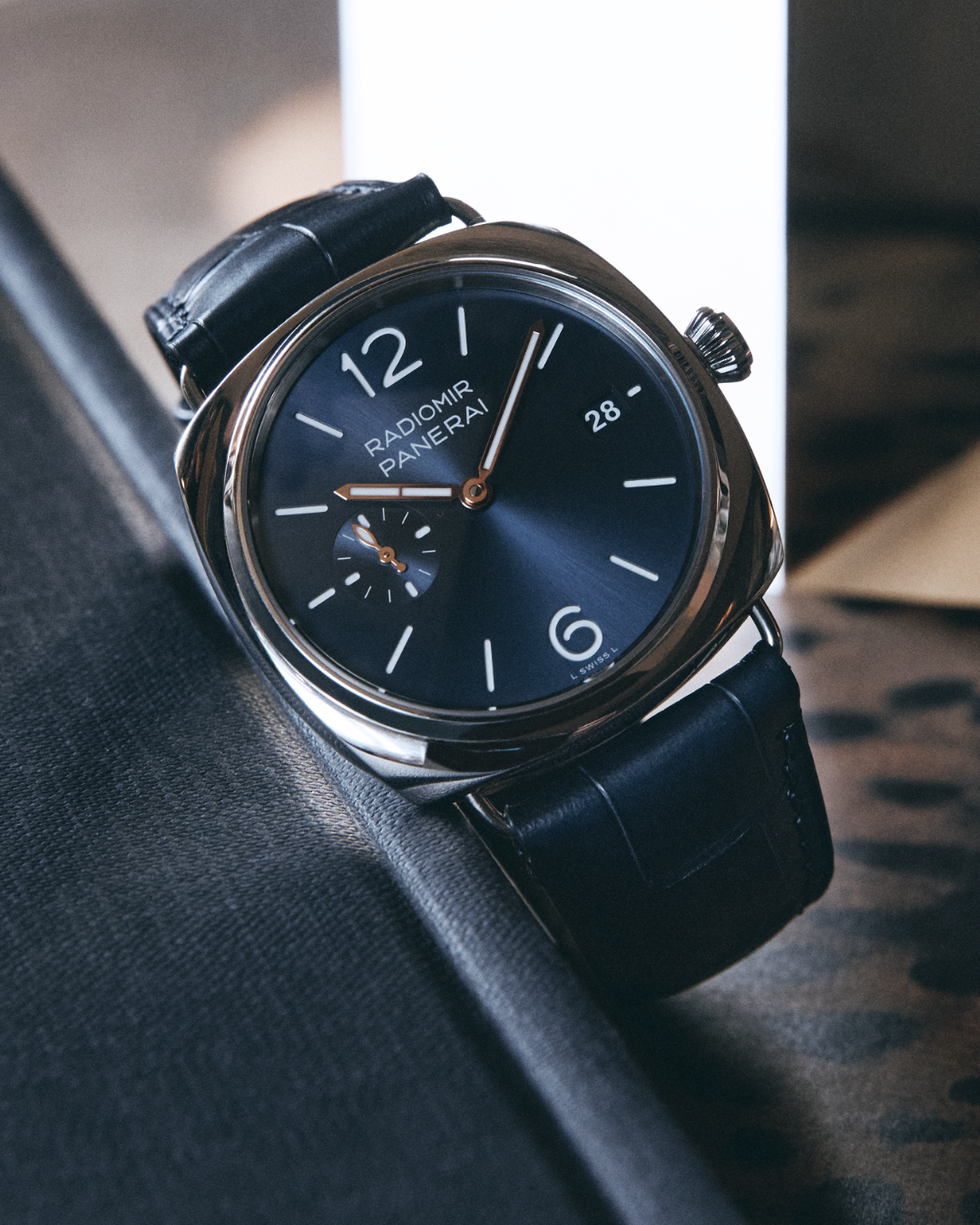 A close-up of a Panerai Radiomir watch with a dark blue dial, silver case, and black leather strap.