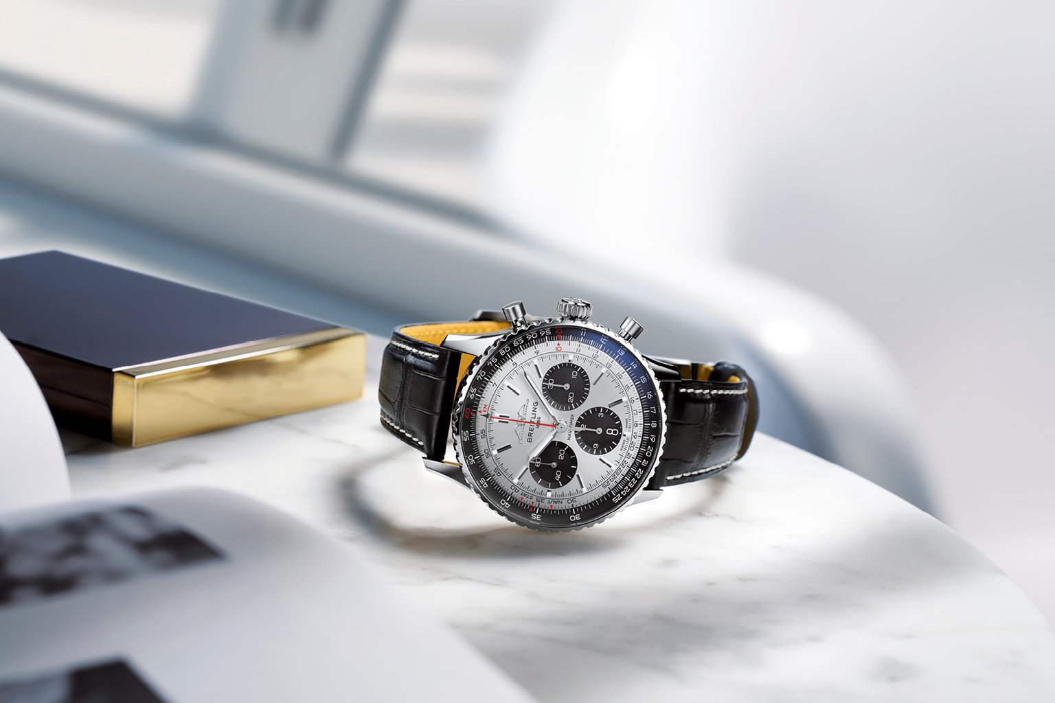 A Breitling "Navitimer" with a black leather strap and a tachymeter bezel, lying on a table.