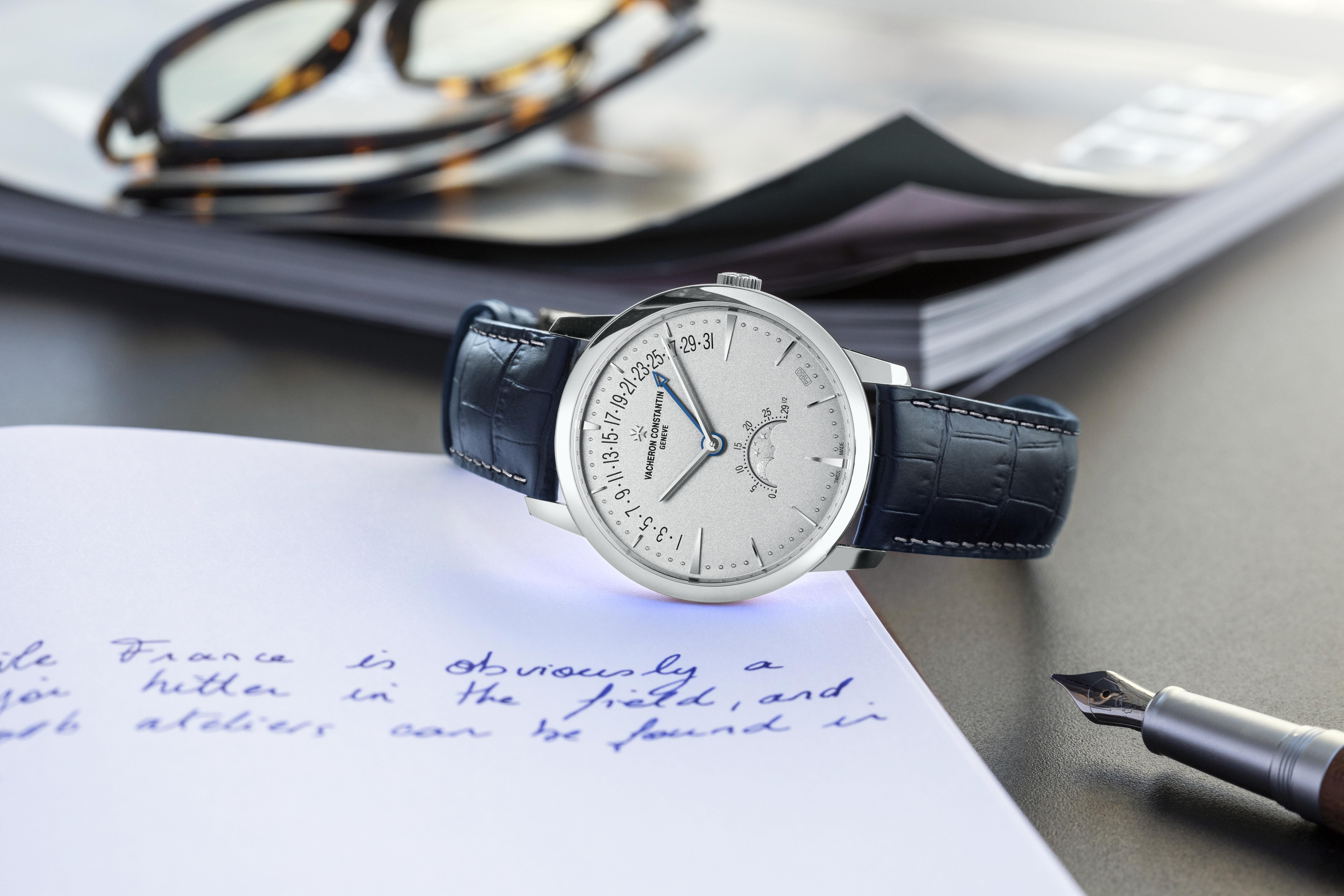 Elegant Vacheron Constantin watch with date and moon phase display on leather strap, placed beside handwritten notes.
