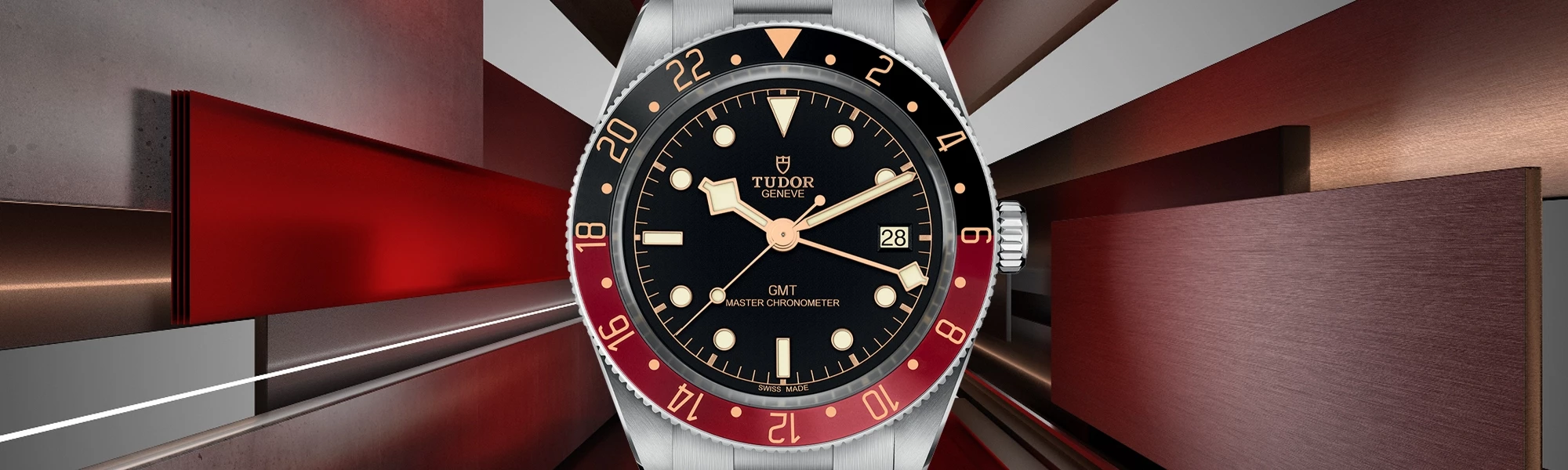 Gros plan sur la montre Tudor GMT avec un cadran noir, des index crème, une lunette rouge et bleue 'Pepsi', et un boîtier en acier inoxydable. L'arrière-plan présente des accents métalliques et rouges dynamiques, soulignant le design audacieux et fonctionnel de la montre et l'héritage de Tudor en matière d’artisanat.