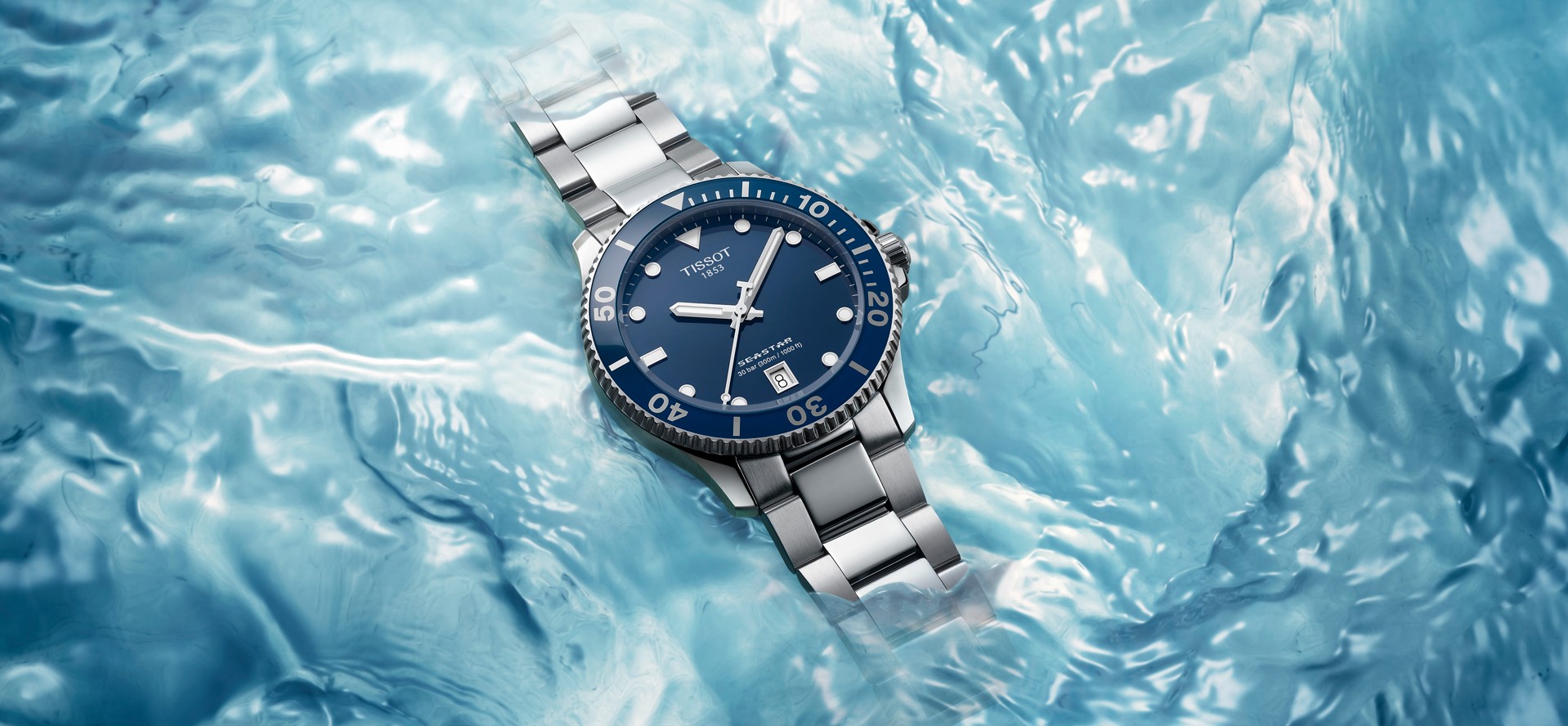 Close-up of the Tissot Seastar watch with a deep blue dial and matching bezel, set against a background of swirling ocean waves. The watch's stainless steel bracelet and high water resistance highlight its design for underwater exploration and rugged elegance.