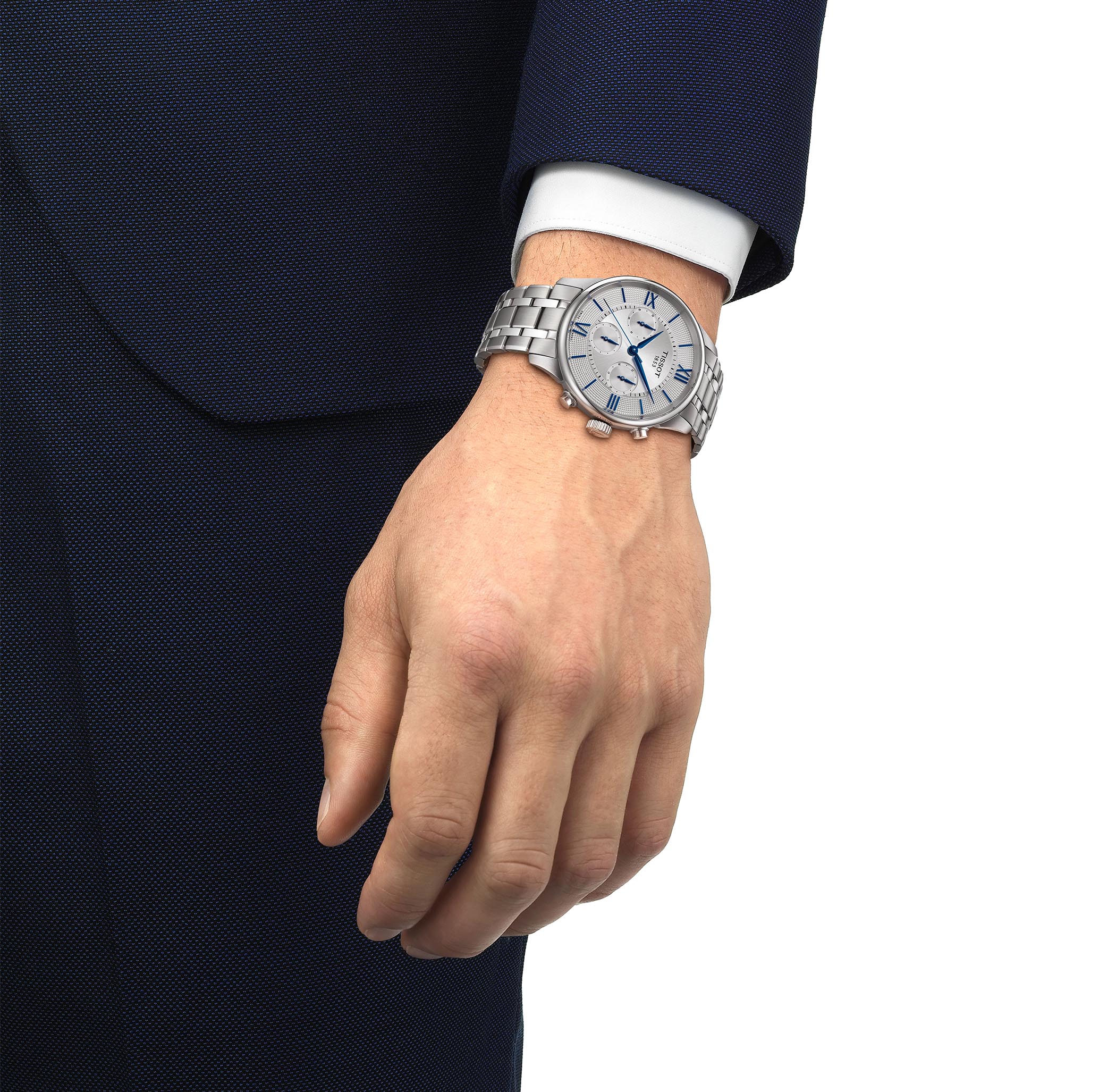 A Tissot Chemin des Tourelles with a silver stainless steel bracelet and a silver-tone dial. The watch features three subdials, blue hands and hour markers, and Roman numerals