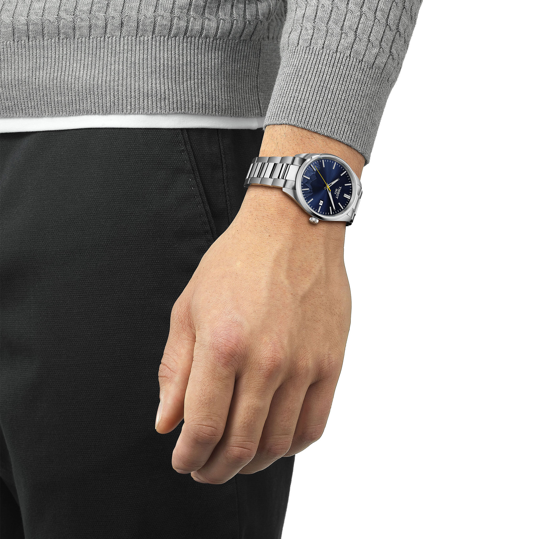 TISSOT PR 100 with a silver stainless steel bracelet and a blue dial, worn on a wrist.