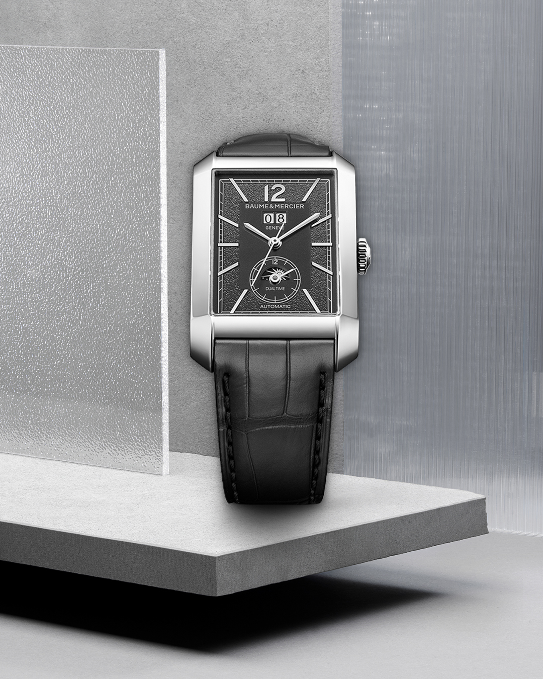 A rectangular Baume & Mercier watch with a black textured dial, silver case, and black alligator leather strap.