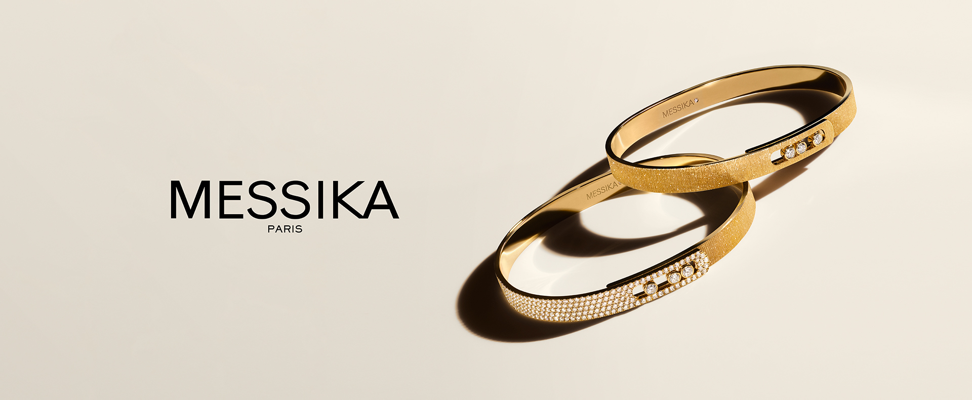 Yellow gold Messika Move bracelets with diamonds on beige background.