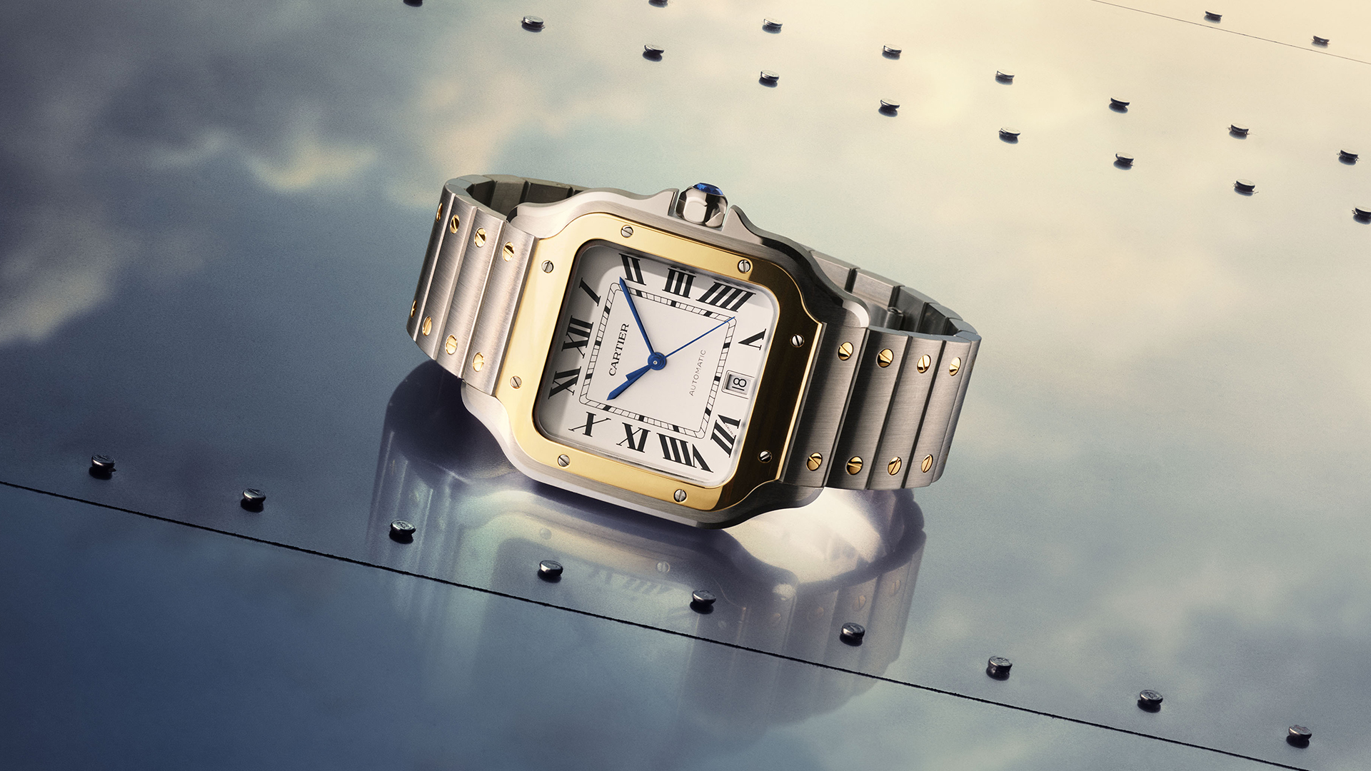 Close-up of a Cartier Santos on the left side of the image. On the right, it is worn on a man's wrist.