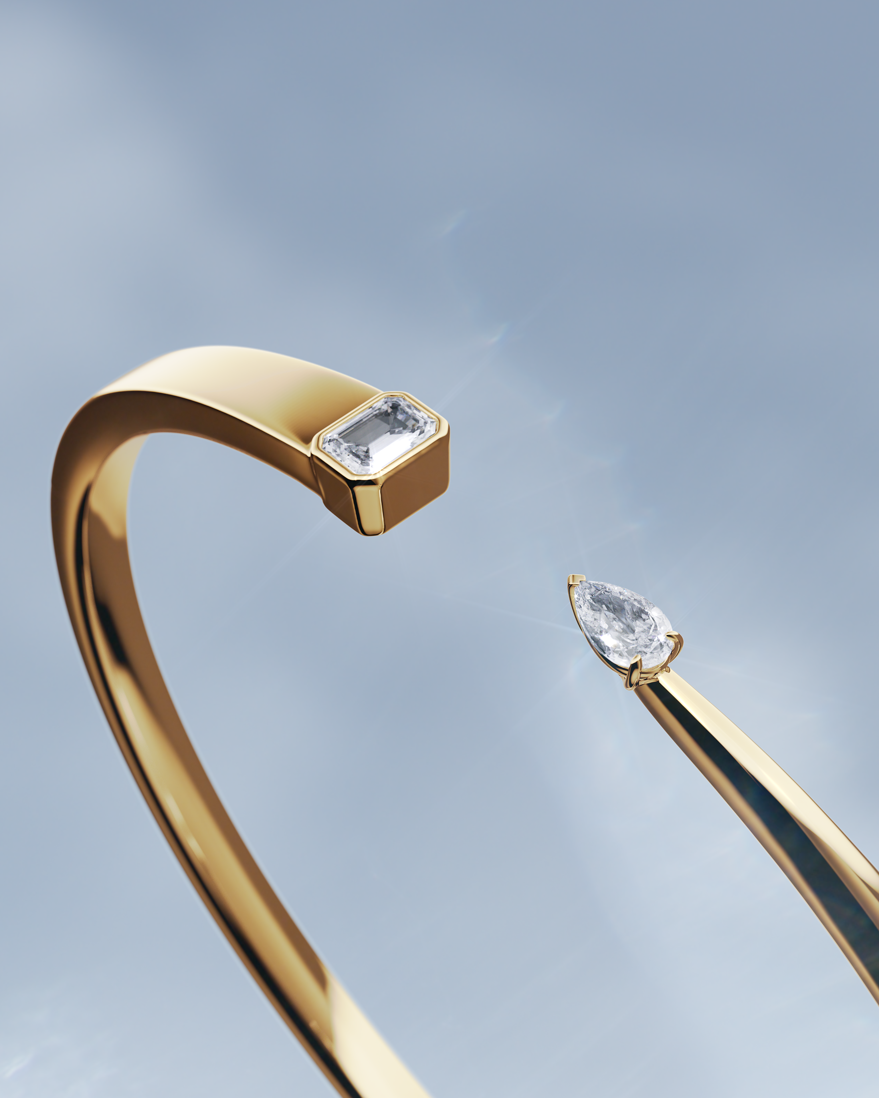 A gold cuff bracelet with an emerald-cut diamond on one end and a pear-shaped diamond on the other.