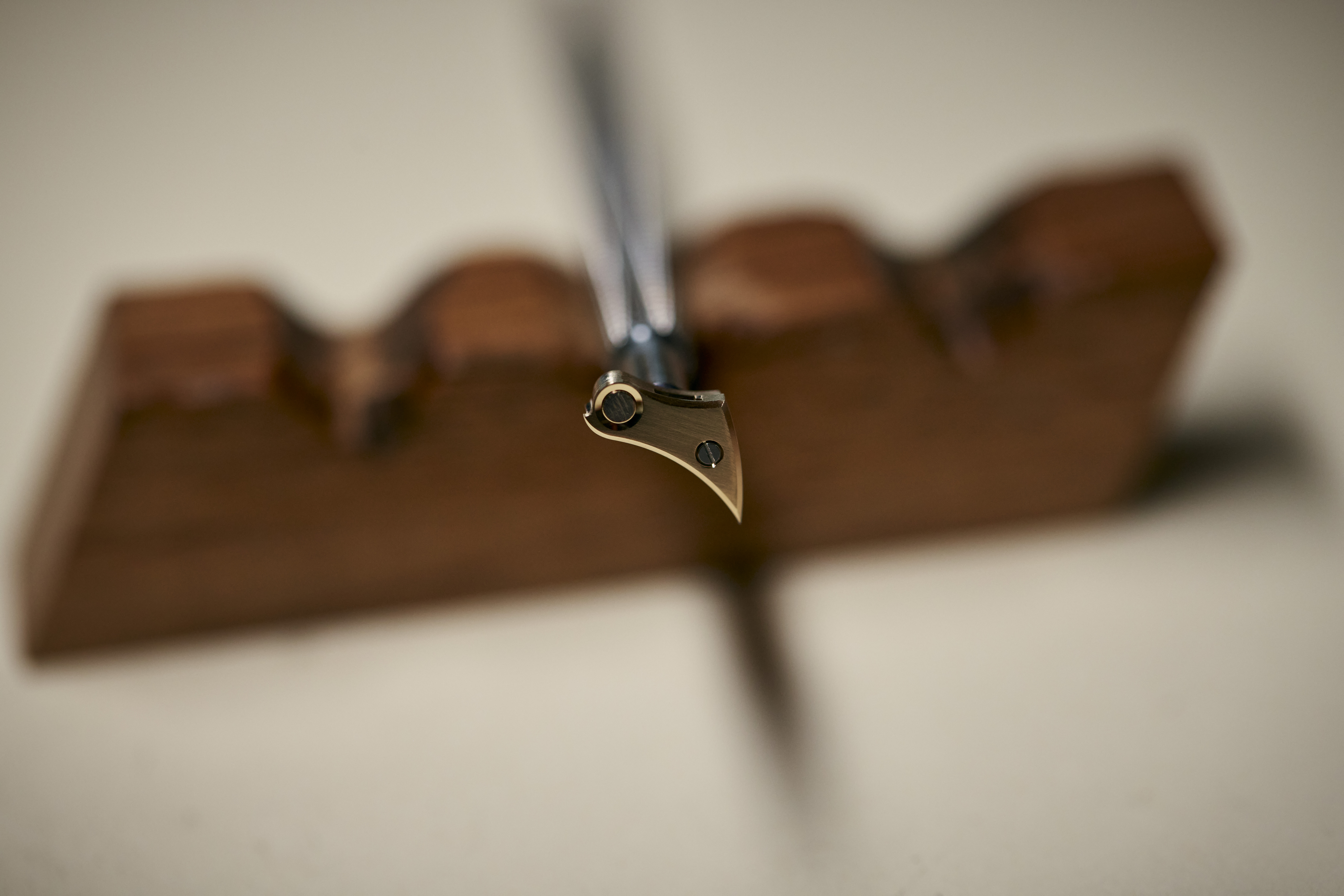 A close-up, shallow depth of field shot of a calligraphy pen nib resting on a wooden pen holder.