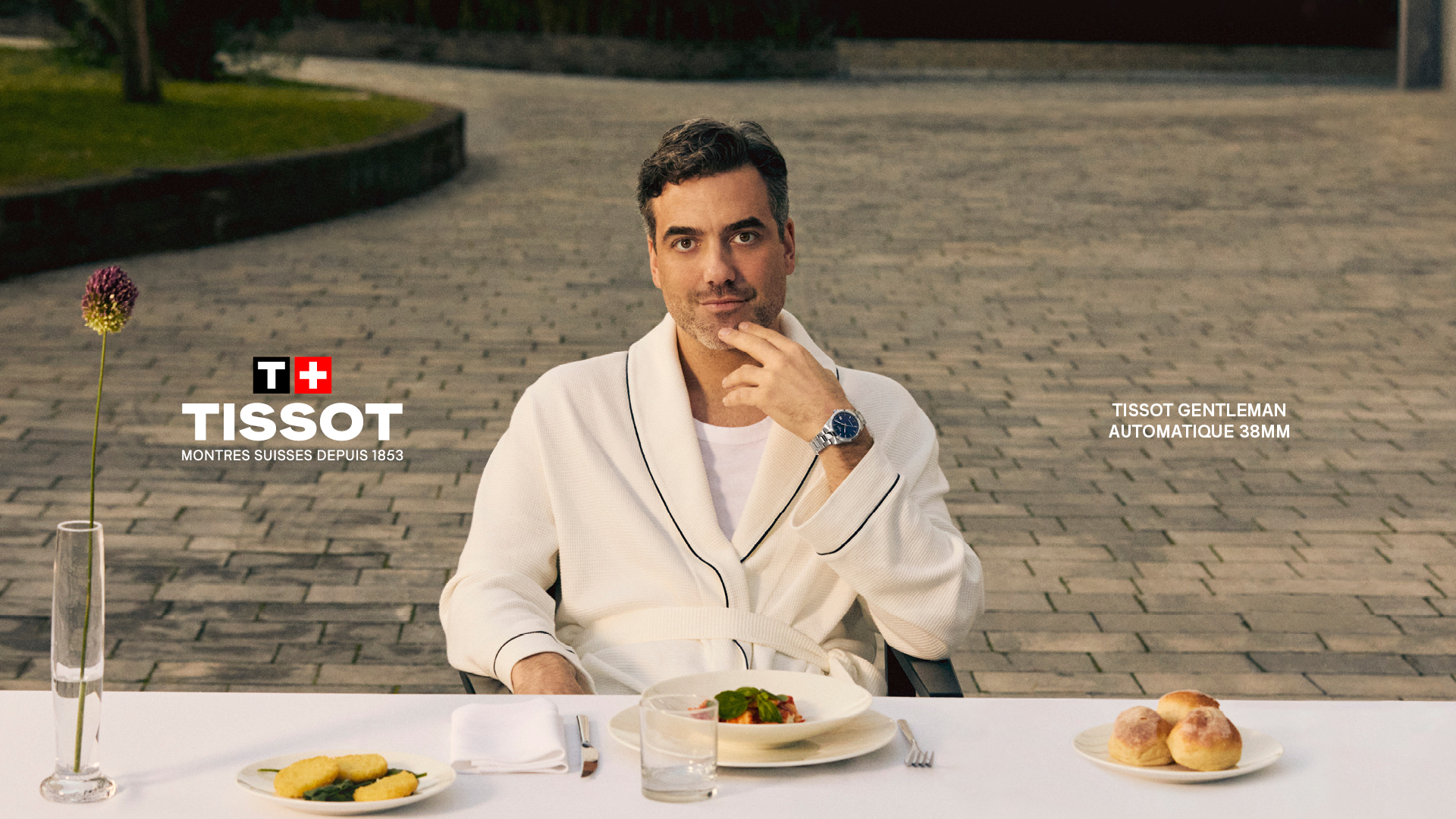 Banner mit der Tissot Seastar Uhr, die ein lebendiges blaues Zifferblatt und eine markante schwarze Lünette aufweist, vor einem Hintergrund ruhiger Meereswellen, eingerahmt von einem Rettungsring. Das Tissot-Logo mit dem Kreuz im Logo ist links sichtbar und betont das Schweizer Erbe und die präzise Handwerkskunst.