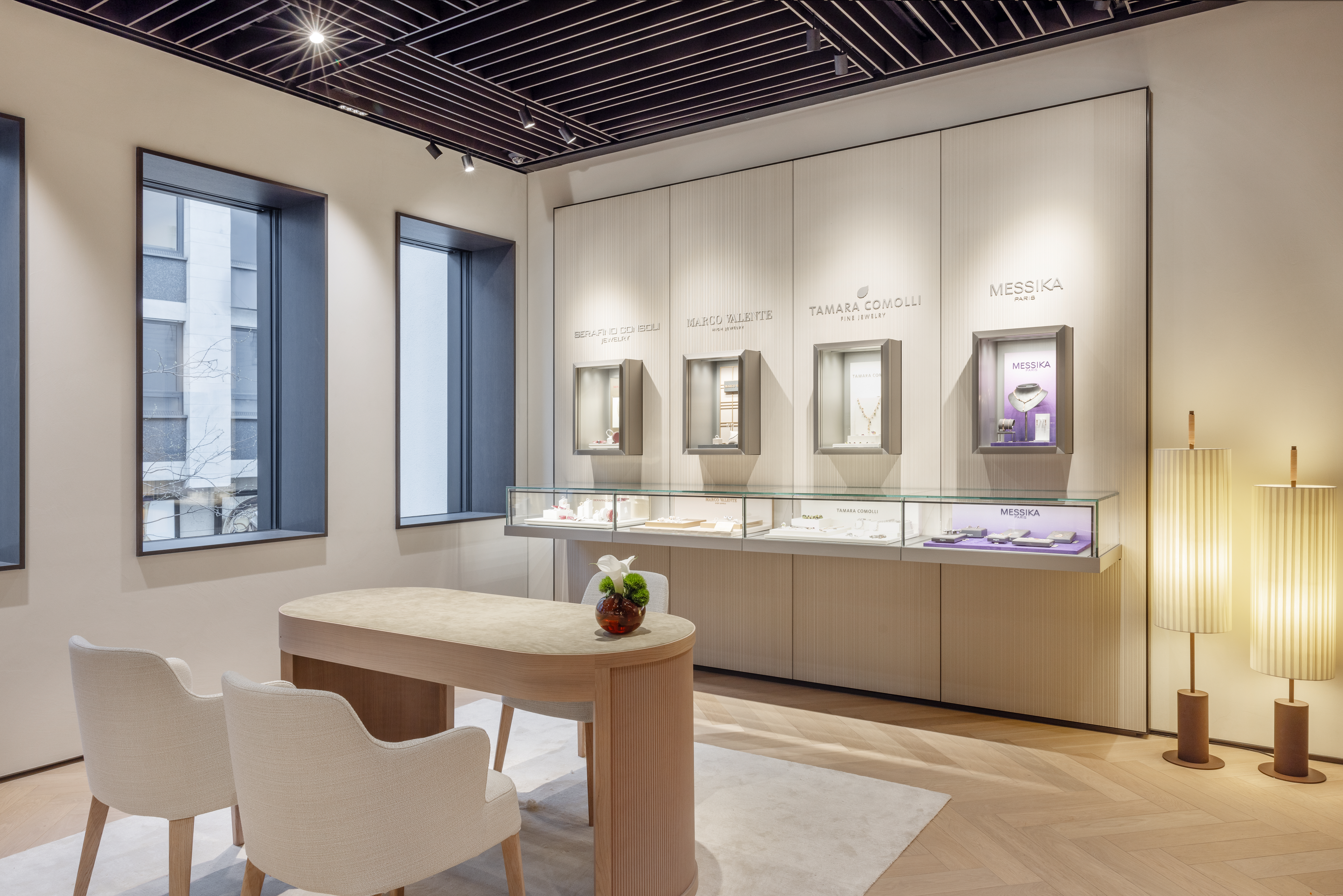 Das Interieur eines modernen Juweliergeschäfts mit Vitrinen, einem hellen Holztisch und zwei Stühlen.