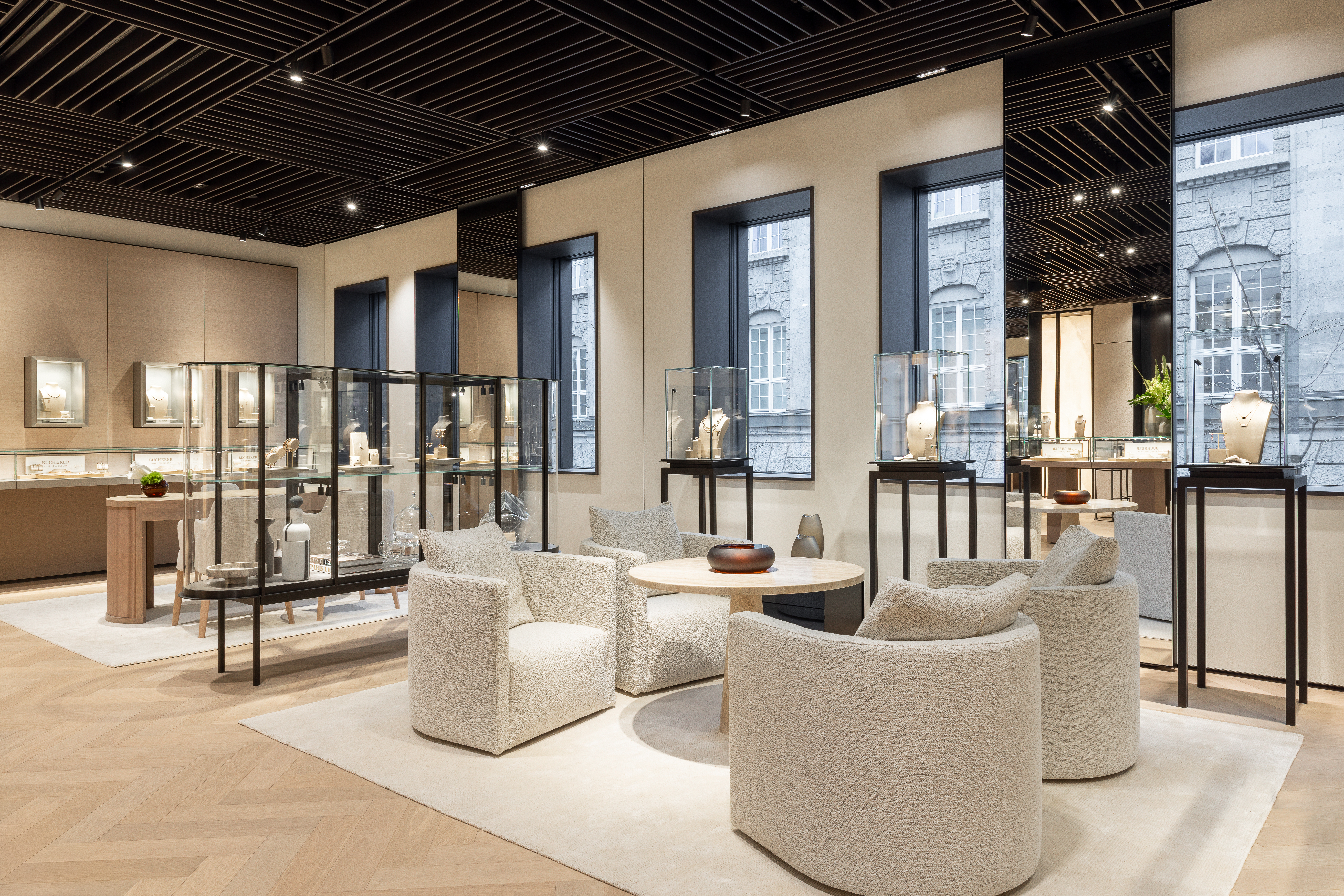 Das Interieur eines luxuriösen Juweliergeschäfts mit Vitrinen, Sitzecke und großen Fenstern.