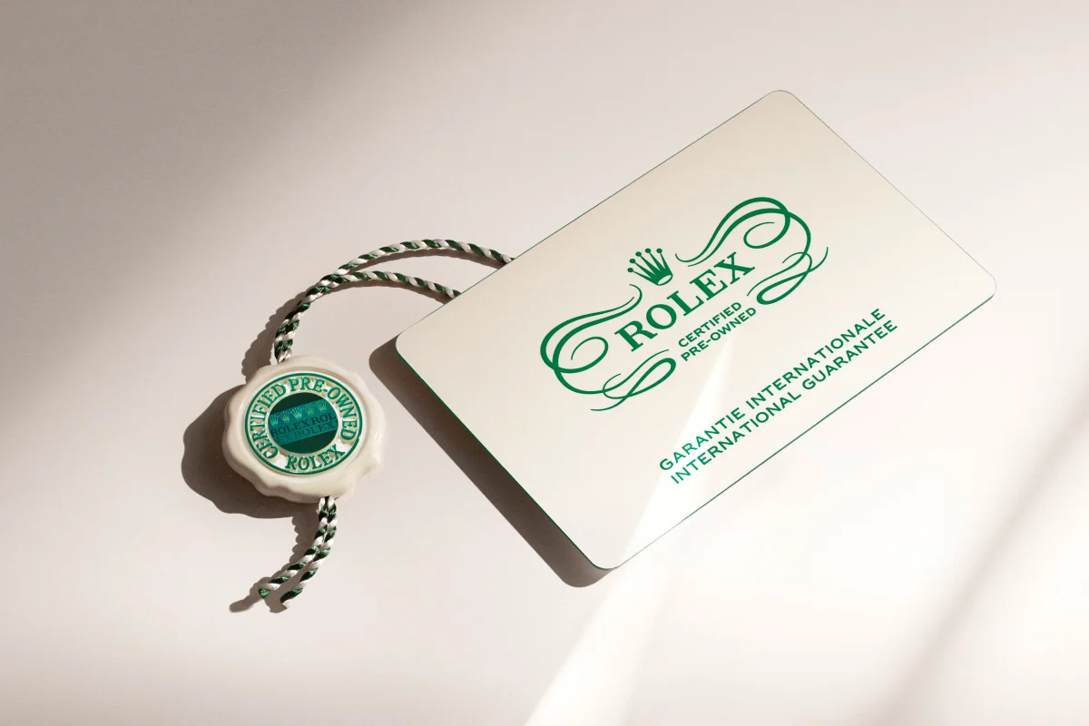 A white Rolex Certified Pre-Owned tag with green text and a green and white seal.