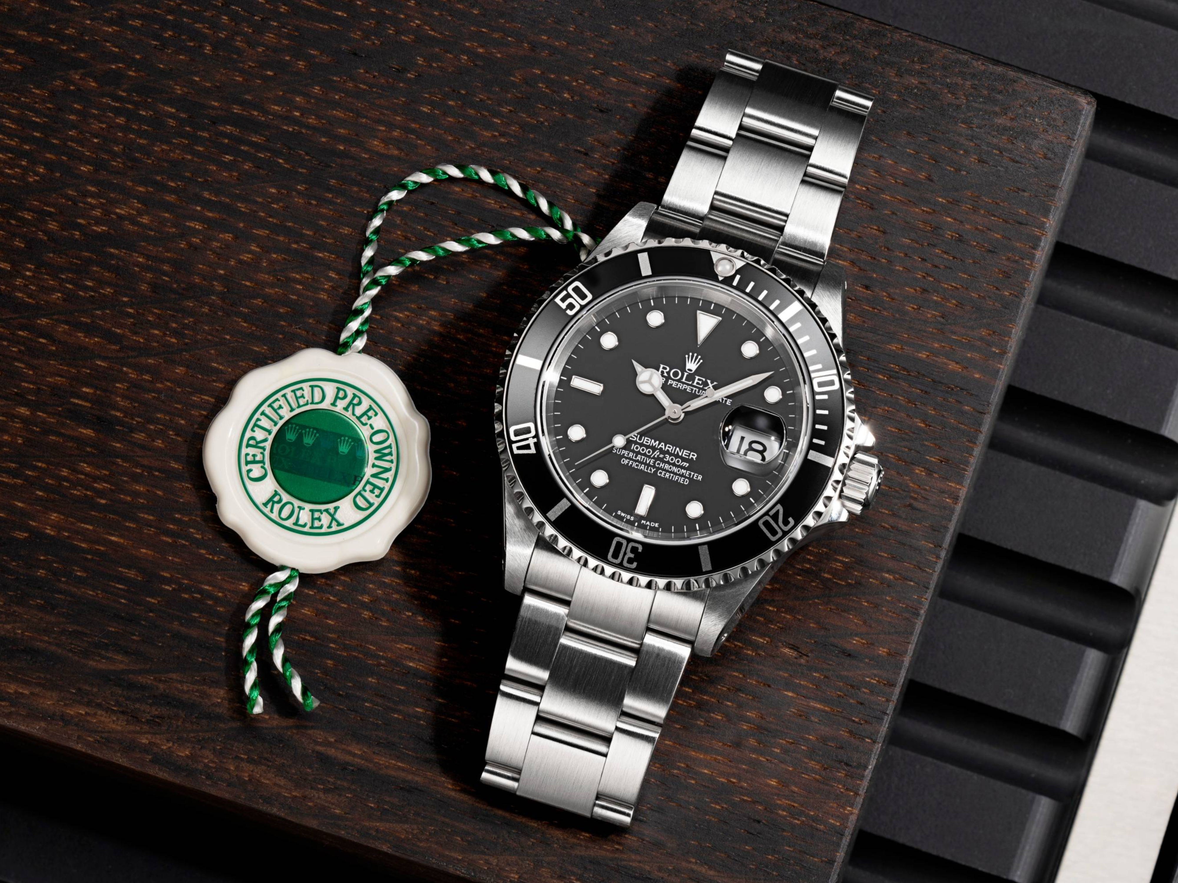 Une montre Rolex Submariner avec cadran noir et bracelet en acier inoxydable, à côté d'une étiquette « Rolex d'occasion certifiée ».