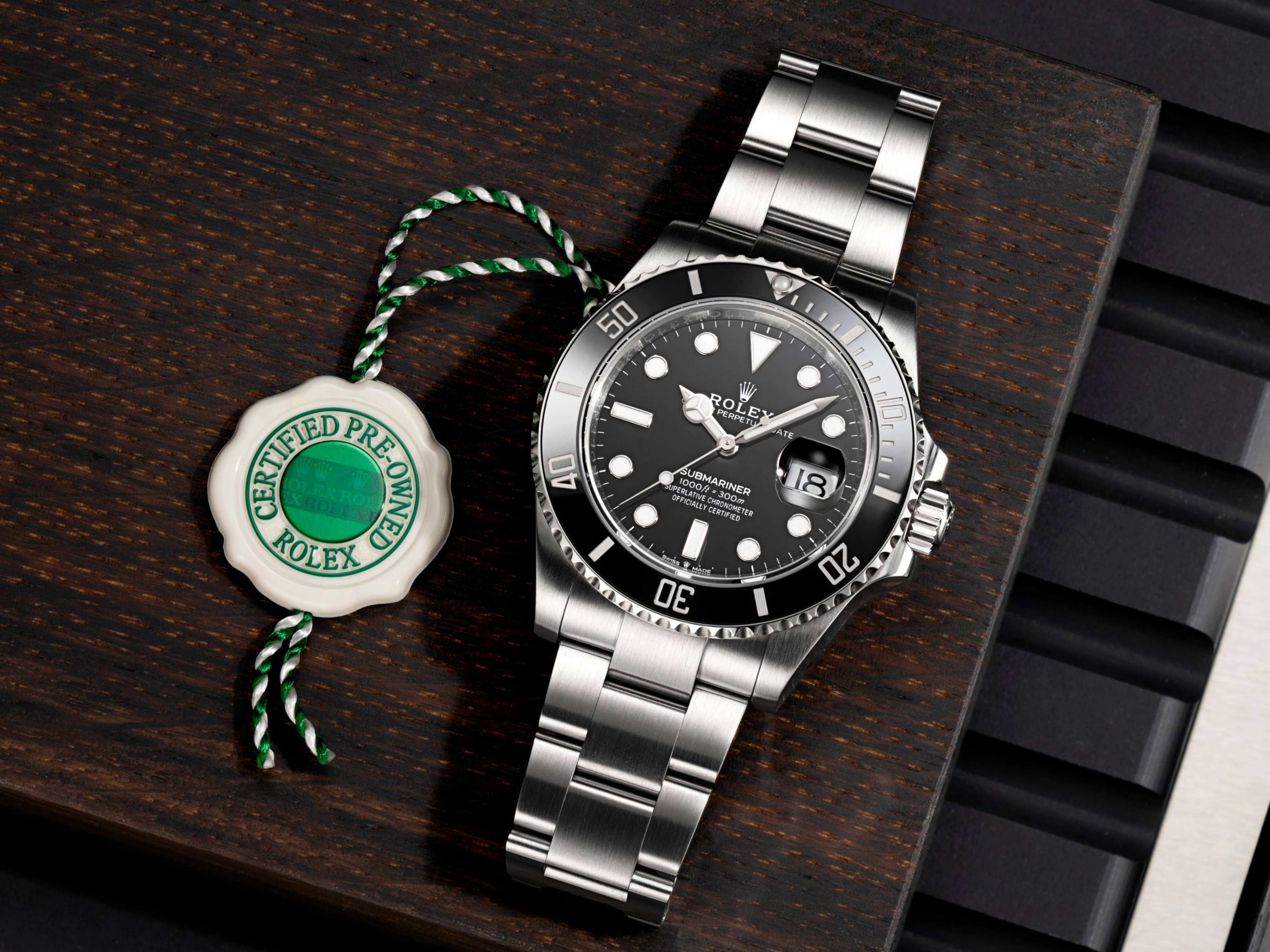 Une montre Rolex Submariner avec cadran noir et bracelet en acier inoxydable, à côté d'une étiquette « Rolex d'occasion certifiée ».