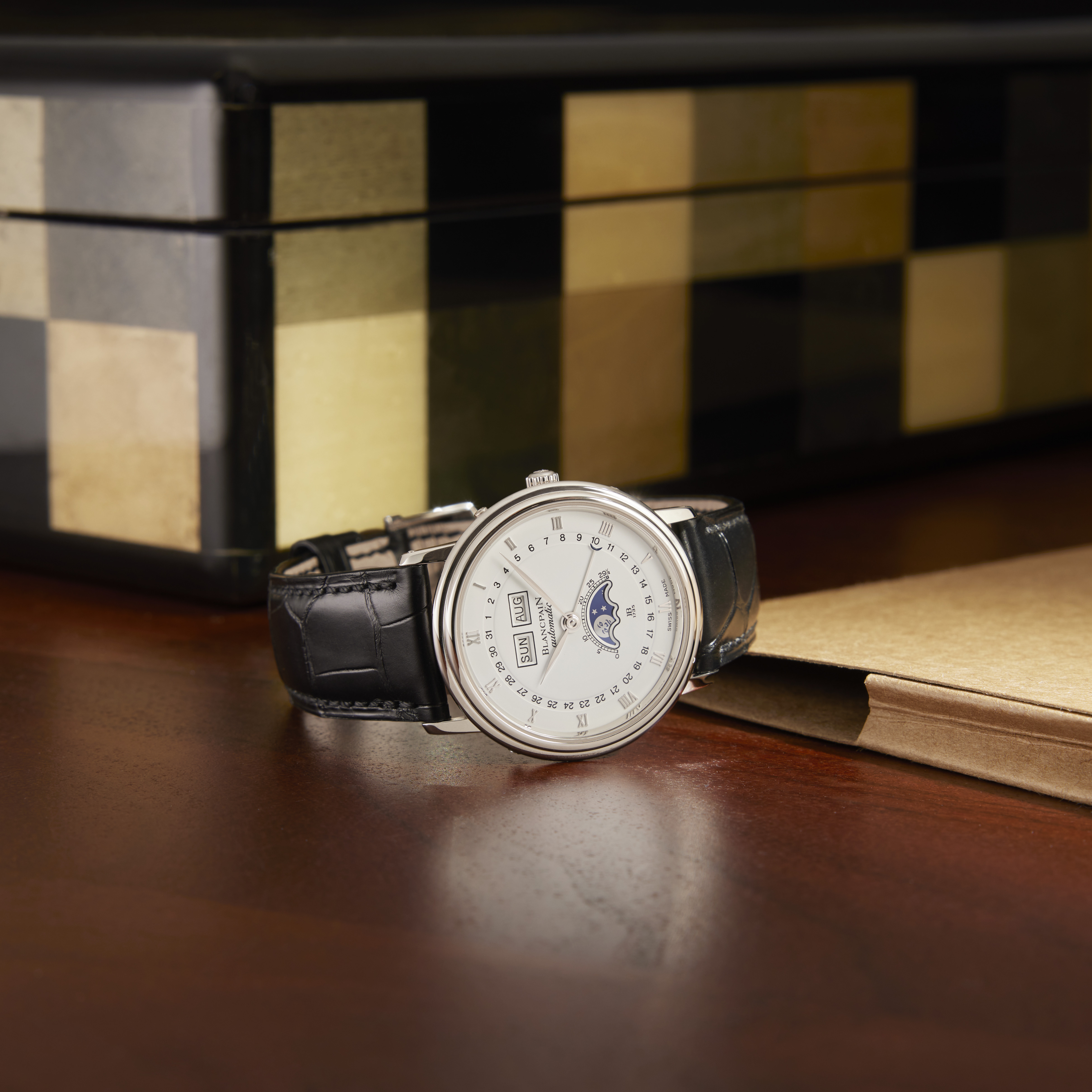 A silver Blancpain Villeret watch with a white face, black leather strap, and moon phase complication.