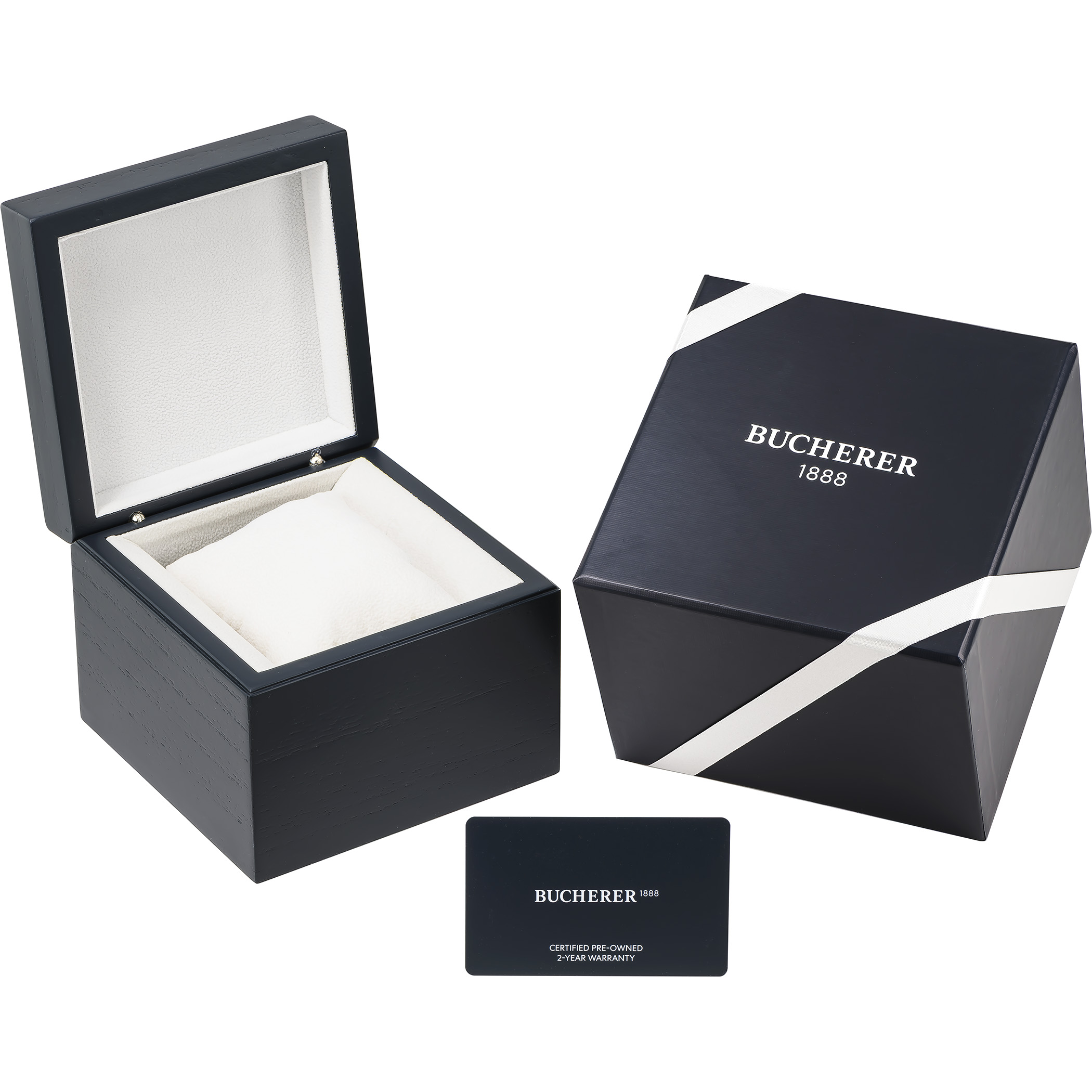 An open dark blue watch box with a white interior, a closed dark blue Bucherer box with white ribbons, and a small dark blue Bucherer card.