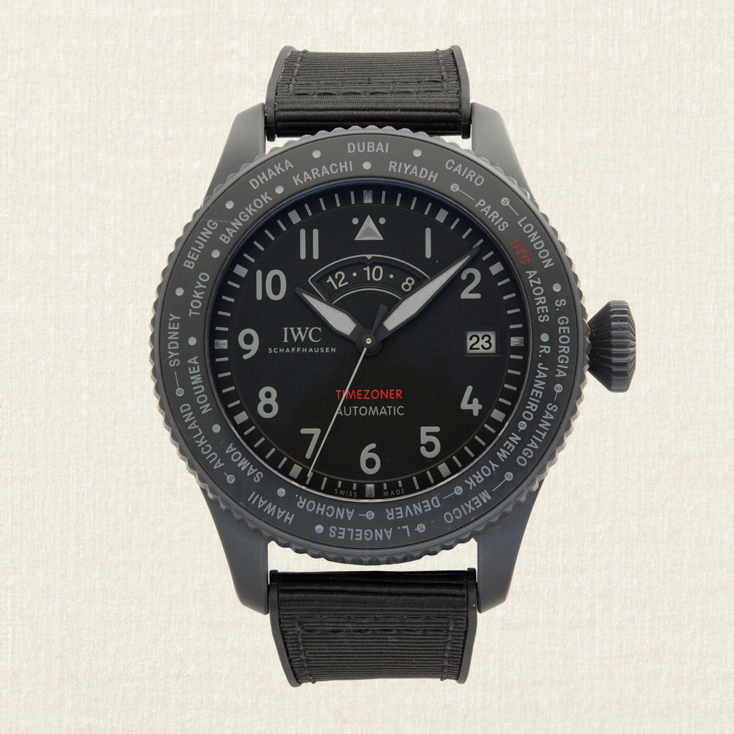 A black IWC Schaffhausen Timezoner automatic watch with a black textile strap and a bezel listing world cities.