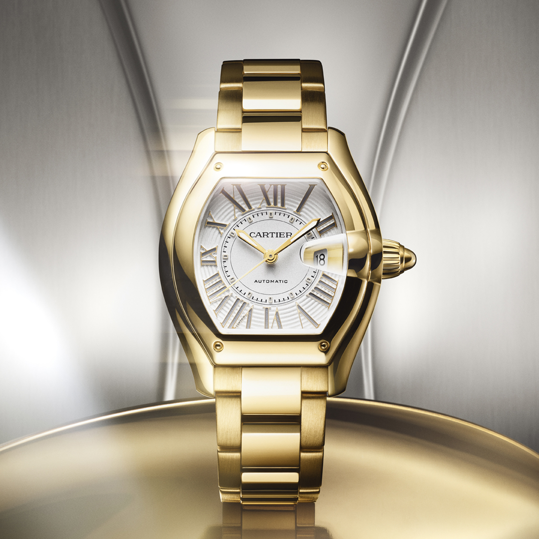A gold Cartier Roadster watch with a white face and Roman numerals.