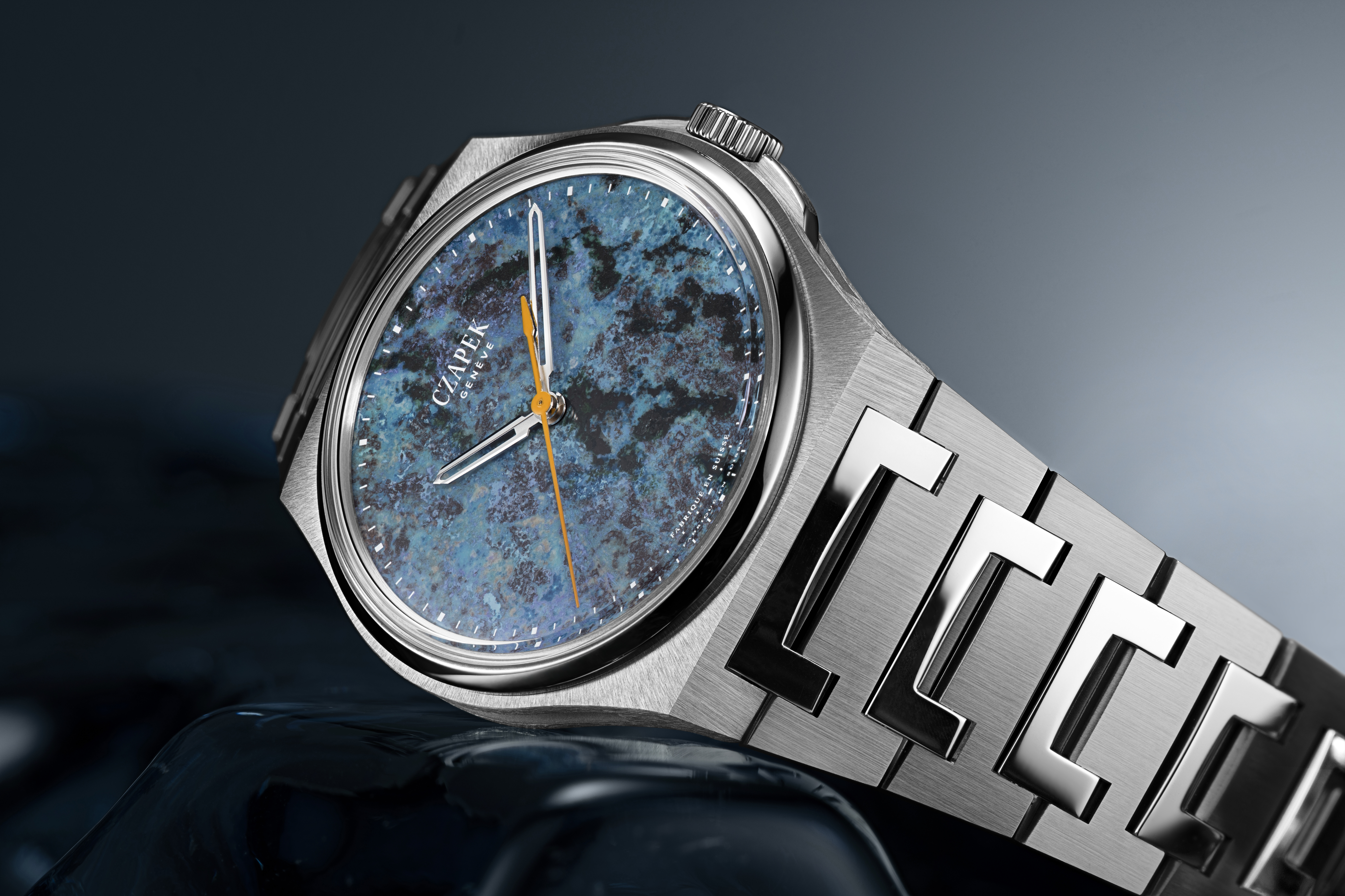 Une montre Czapek & Cie Antarctique Passage de Drake avec un cadran bleu-vert et un bracelet en acier brossé.