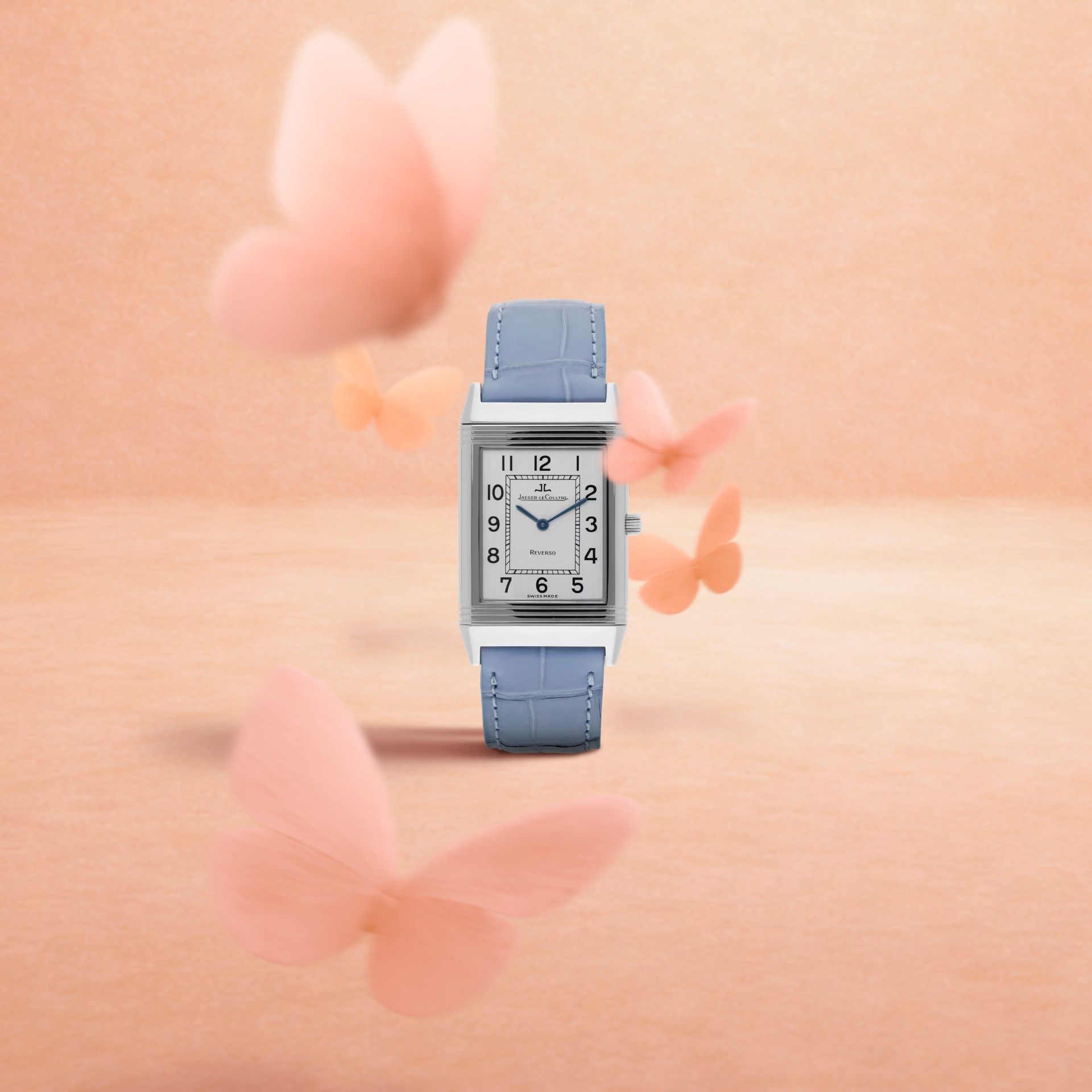 A rectangular silver watch with a light blue leather strap and white face, surrounded by blurred pink butterflies.