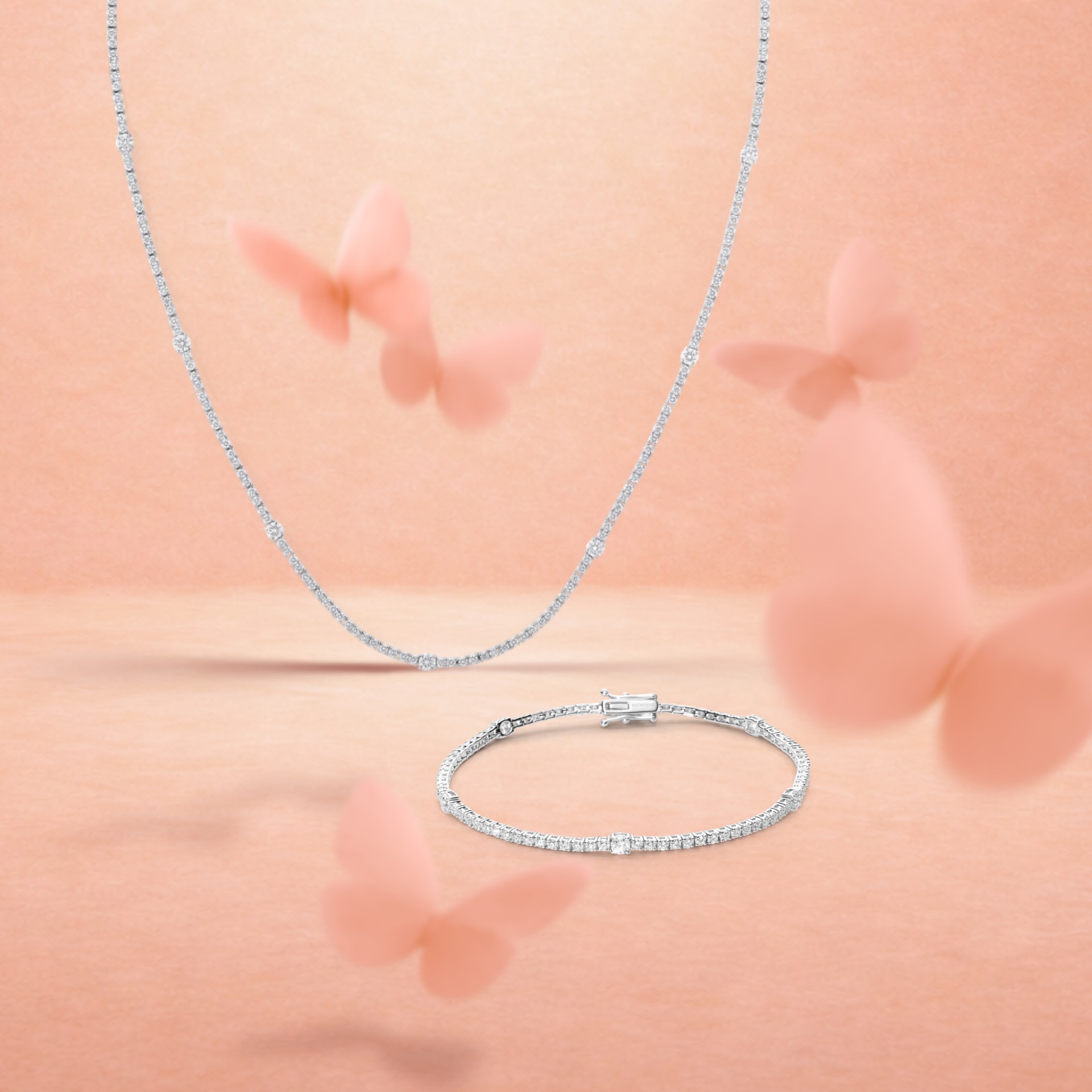 A delicate diamond necklace and bracelet on a peach background with blurred pink butterflies.