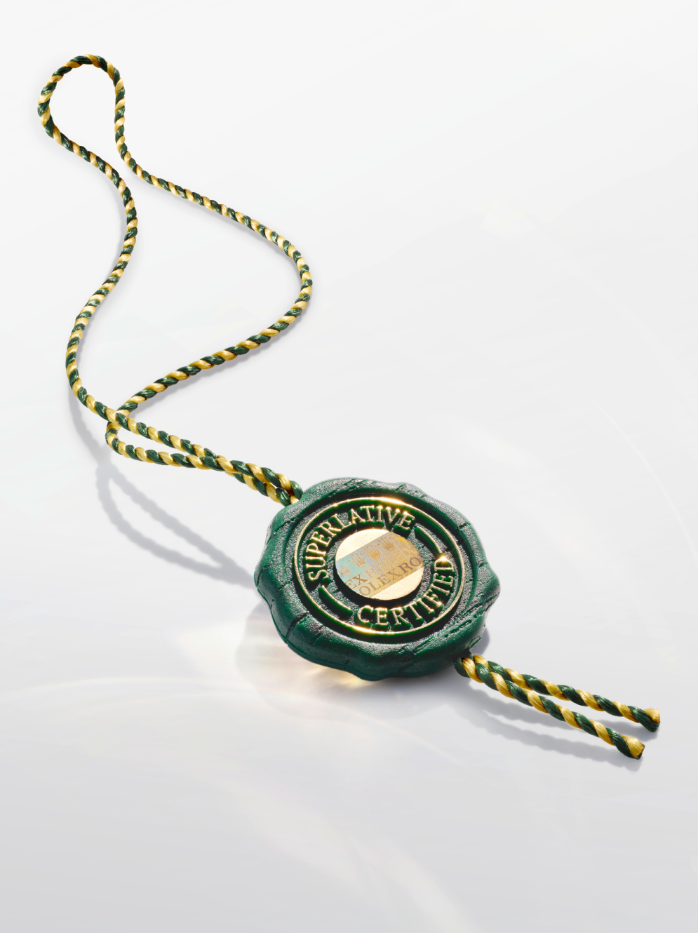 A green and gold Rolex Superlative Chronometer Certified seal with a matching braided cord.
