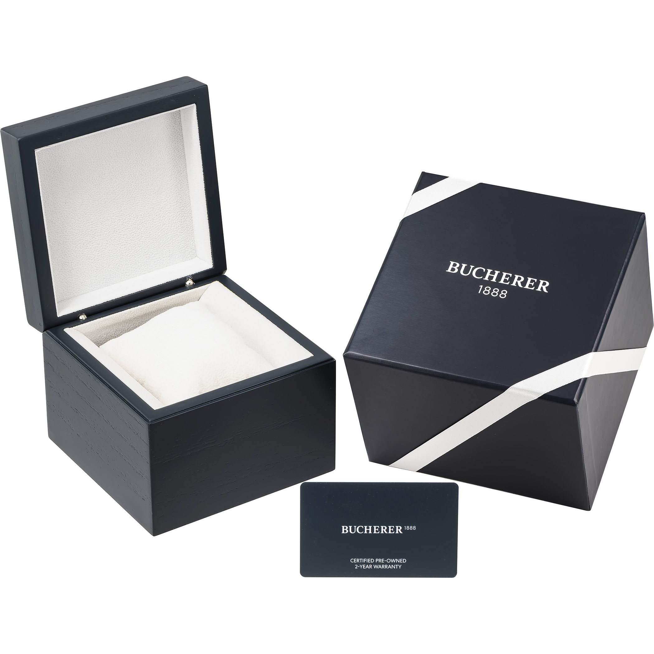 An open dark blue watch box with a white interior, a closed dark blue box with a white ribbon, and a dark blue warranty card.