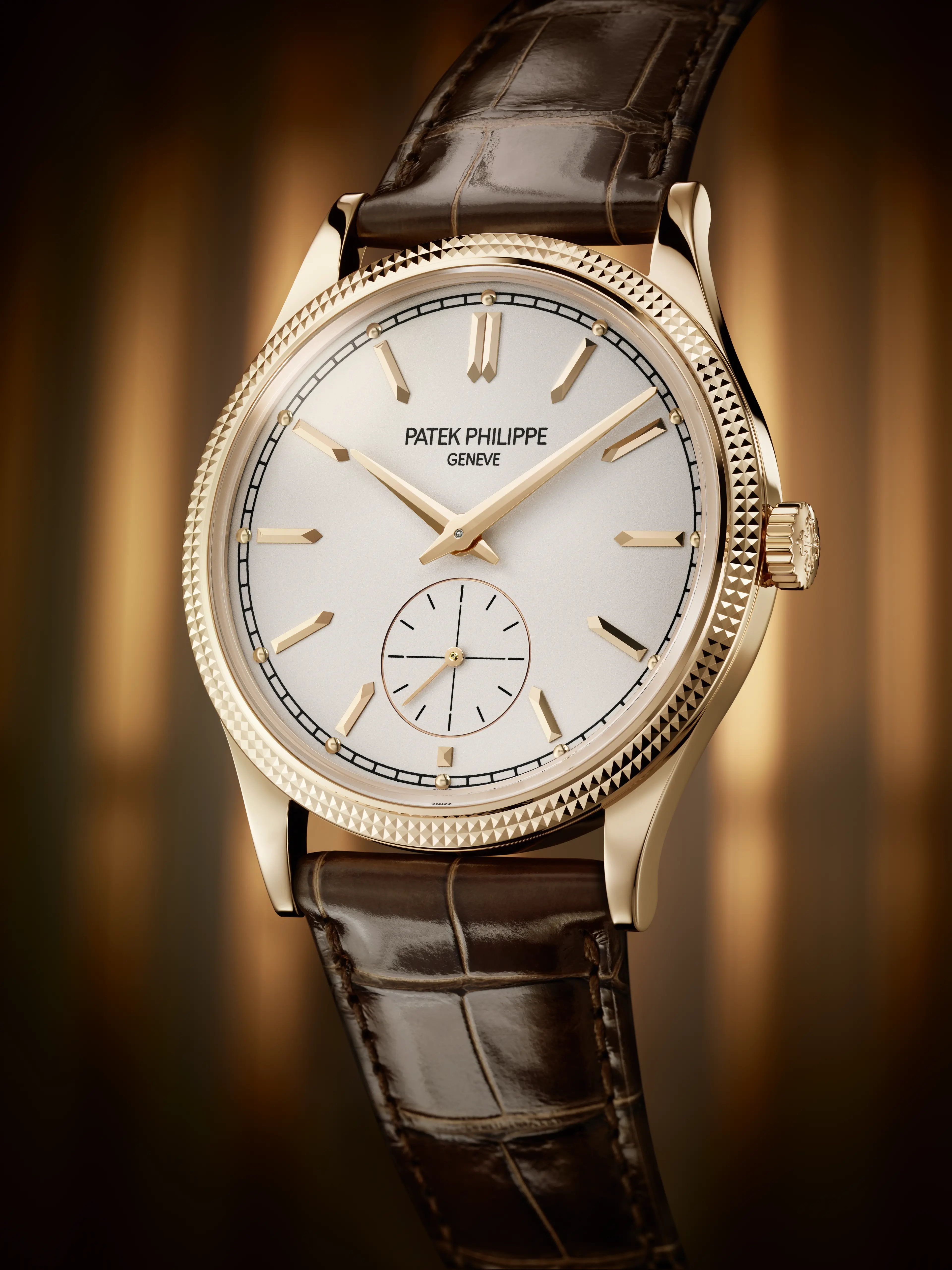 A Patek Philippe Calatrava watch with a rose gold case, white dial, and brown alligator strap.