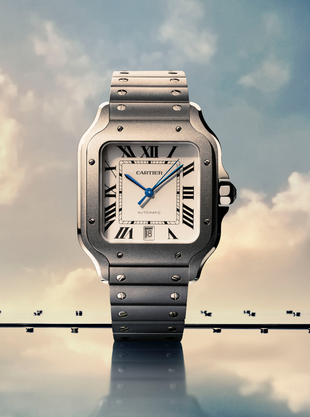 A silver Cartier Santos watch with a white face, Roman numerals, and blue hands, set against a cloudy sky.