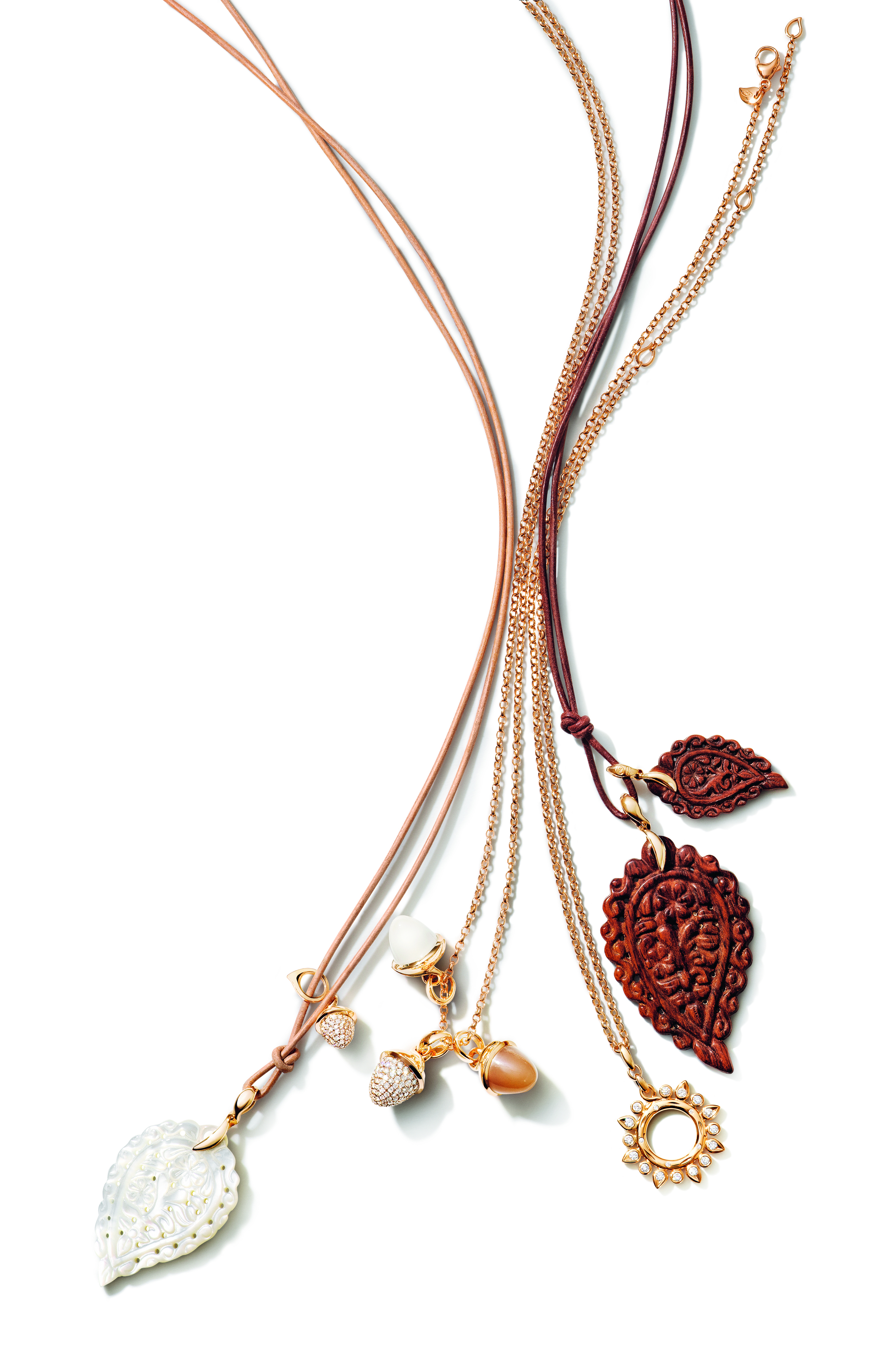 Assortment of necklaces with various pendants, including carved wood, mother-of-pearl, and gold with pearls.