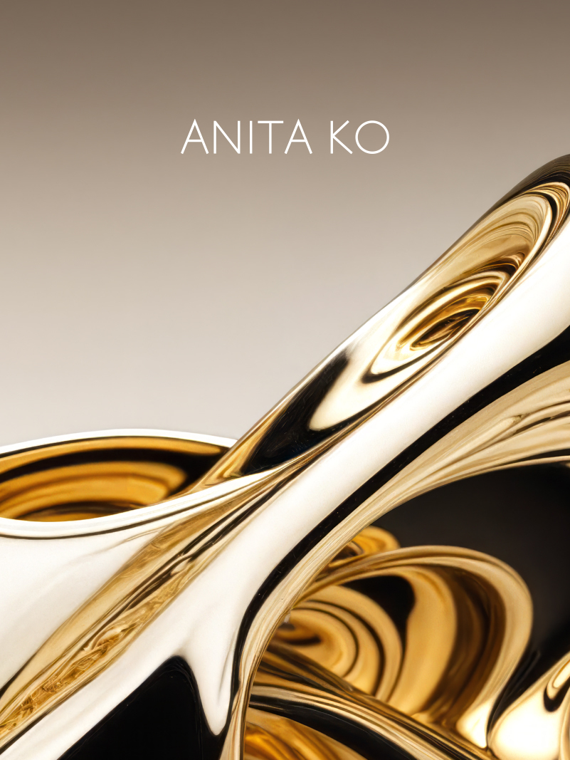 Close-up of a shiny, golden, abstract sculpture with the text "ANITA KO" above it.