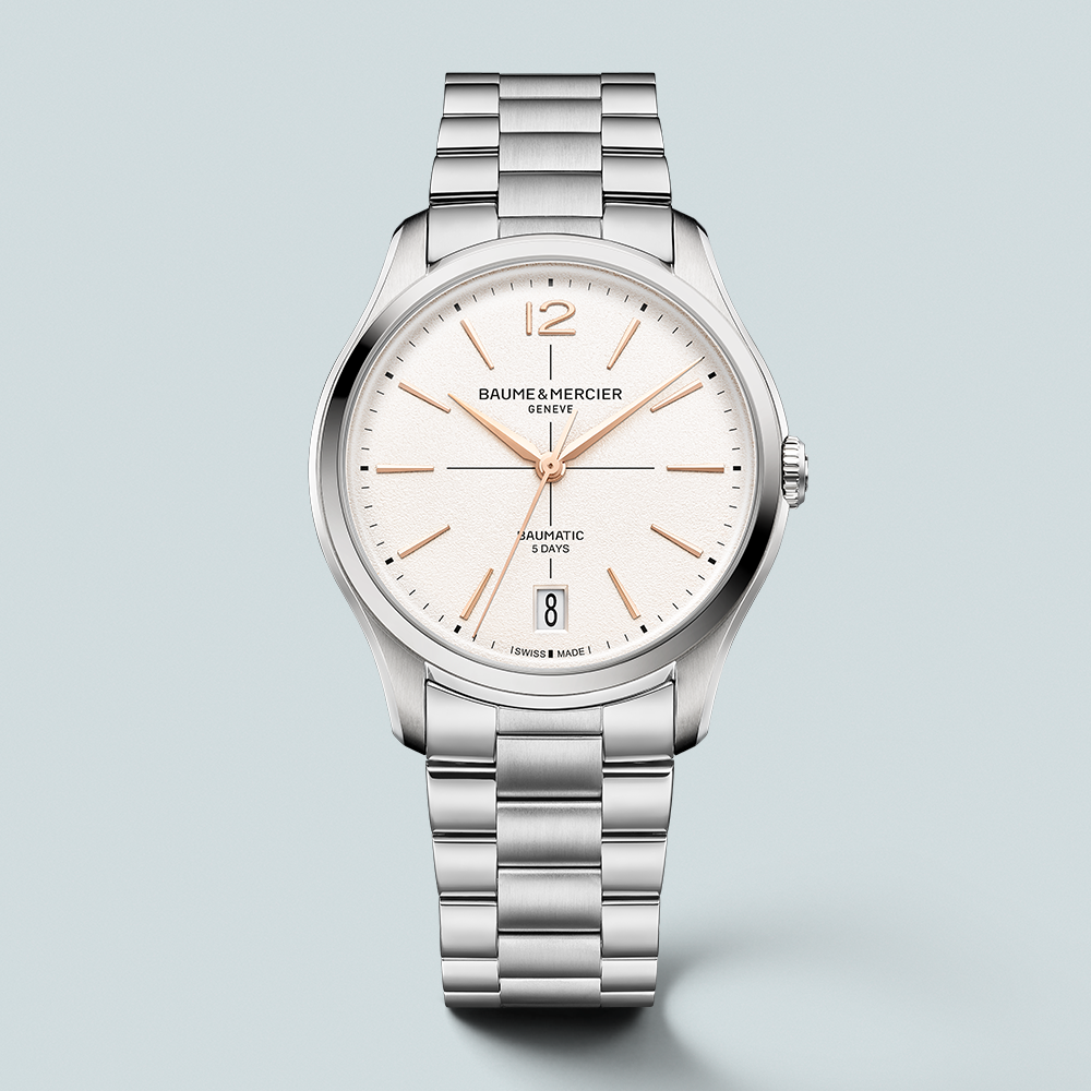 A silver Baume & Mercier automatic watch with a white dial, rose gold hands, and a date window at 6 o'clock.