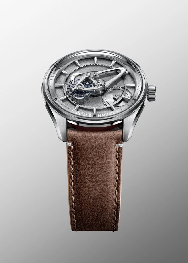 A silver Ulysse Nardin watch with an exposed mechanical movement and a brown leather strap.