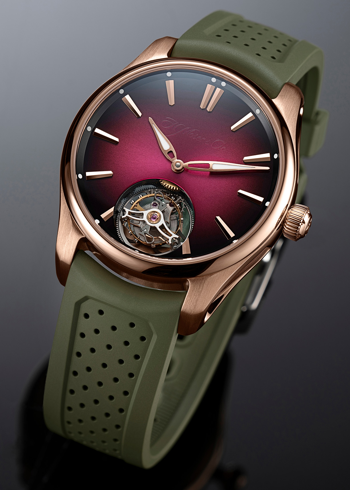 Rose gold watch with a deep red face, exposed tourbillon, and olive green perforated rubber strap.