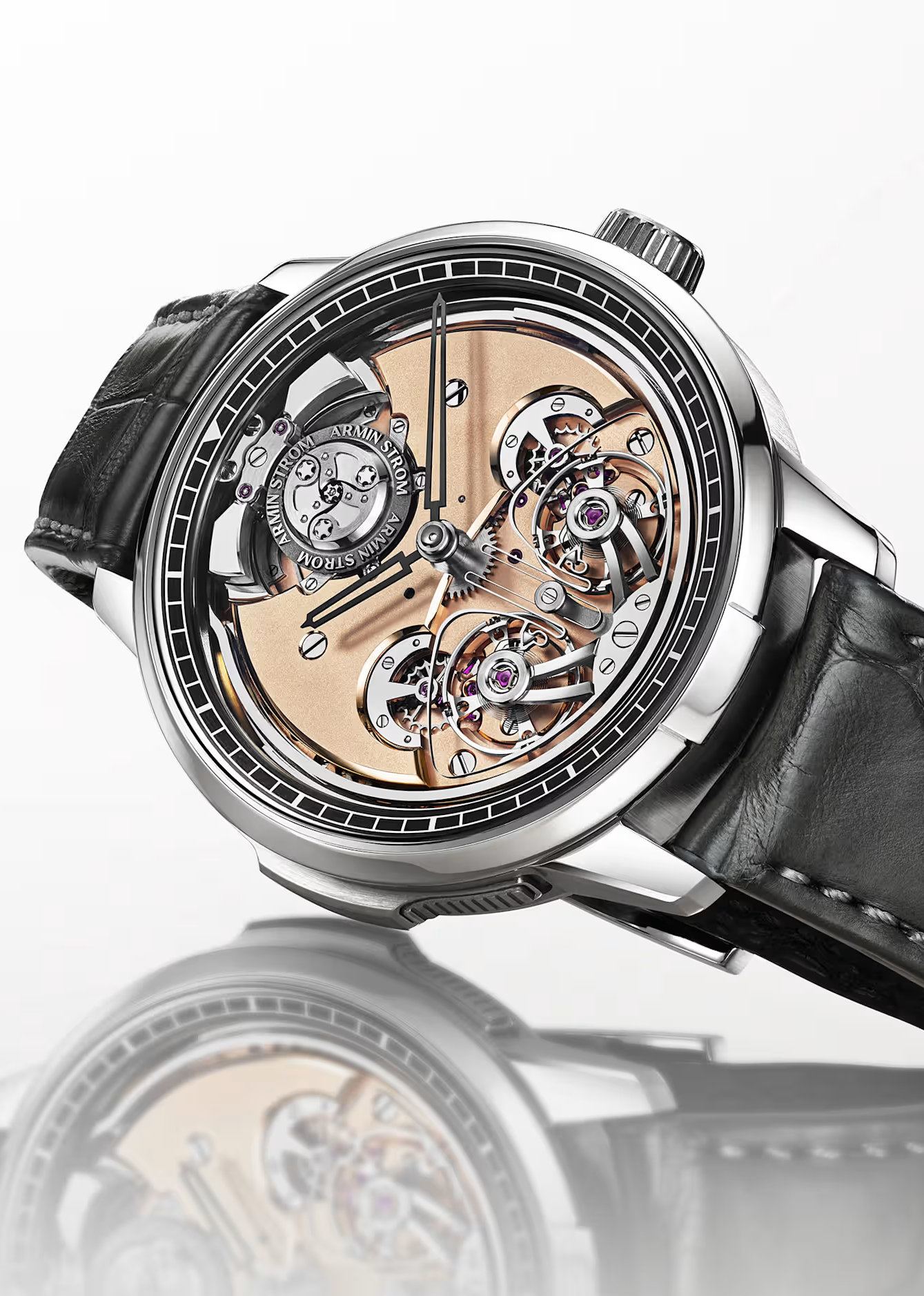 A close-up of a silver-cased wristwatch with a black leather strap, featuring an exposed mechanical movement with gold and silver gears.