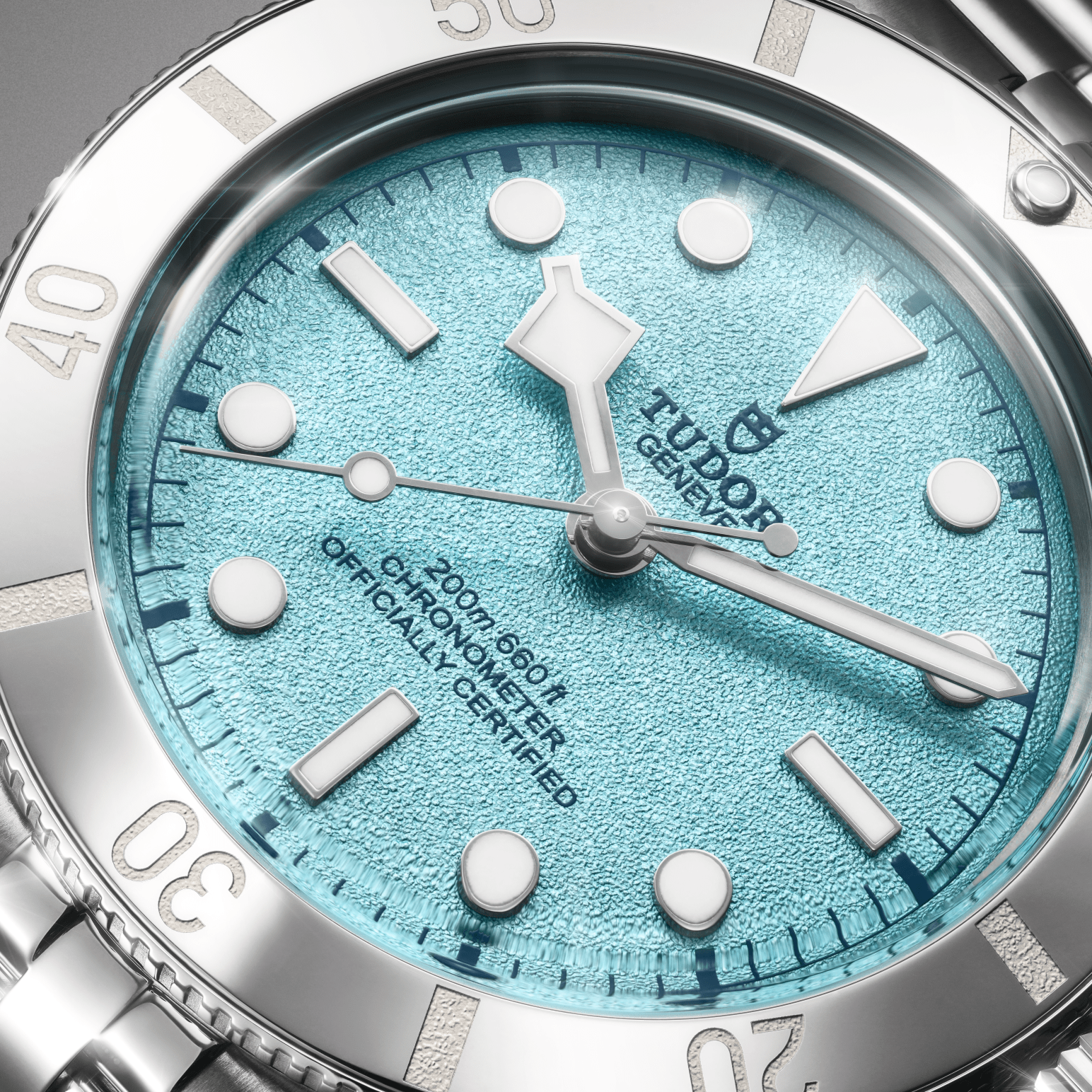 Close-up of a silver watch with a textured light blue face and white hour markers.