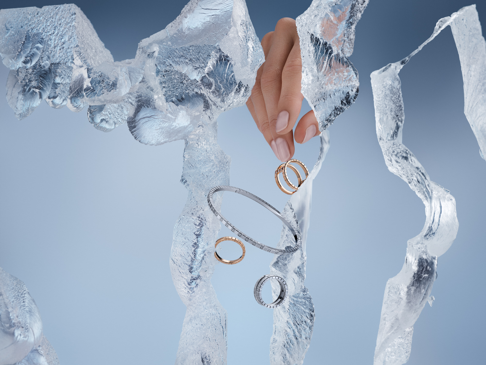 Eine Hand hält einen Goldring inmitten von Eisformationen, während andere Ringe und ein Armband in der Luft schweben.