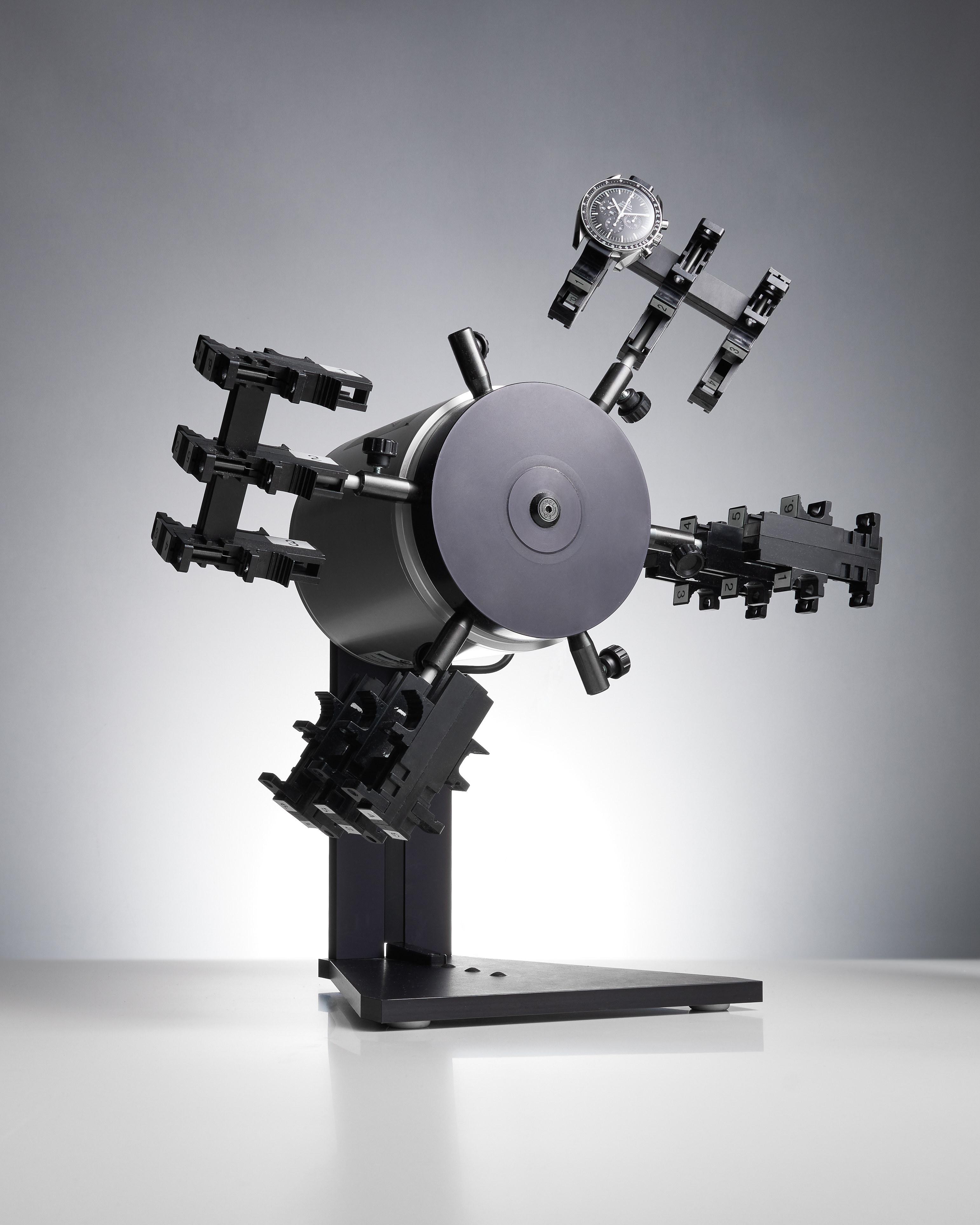Ein schwarzer Uhrenbeweger, an dessen einem drehbaren Arm eine einzelne Chronographenuhr befestigt ist.