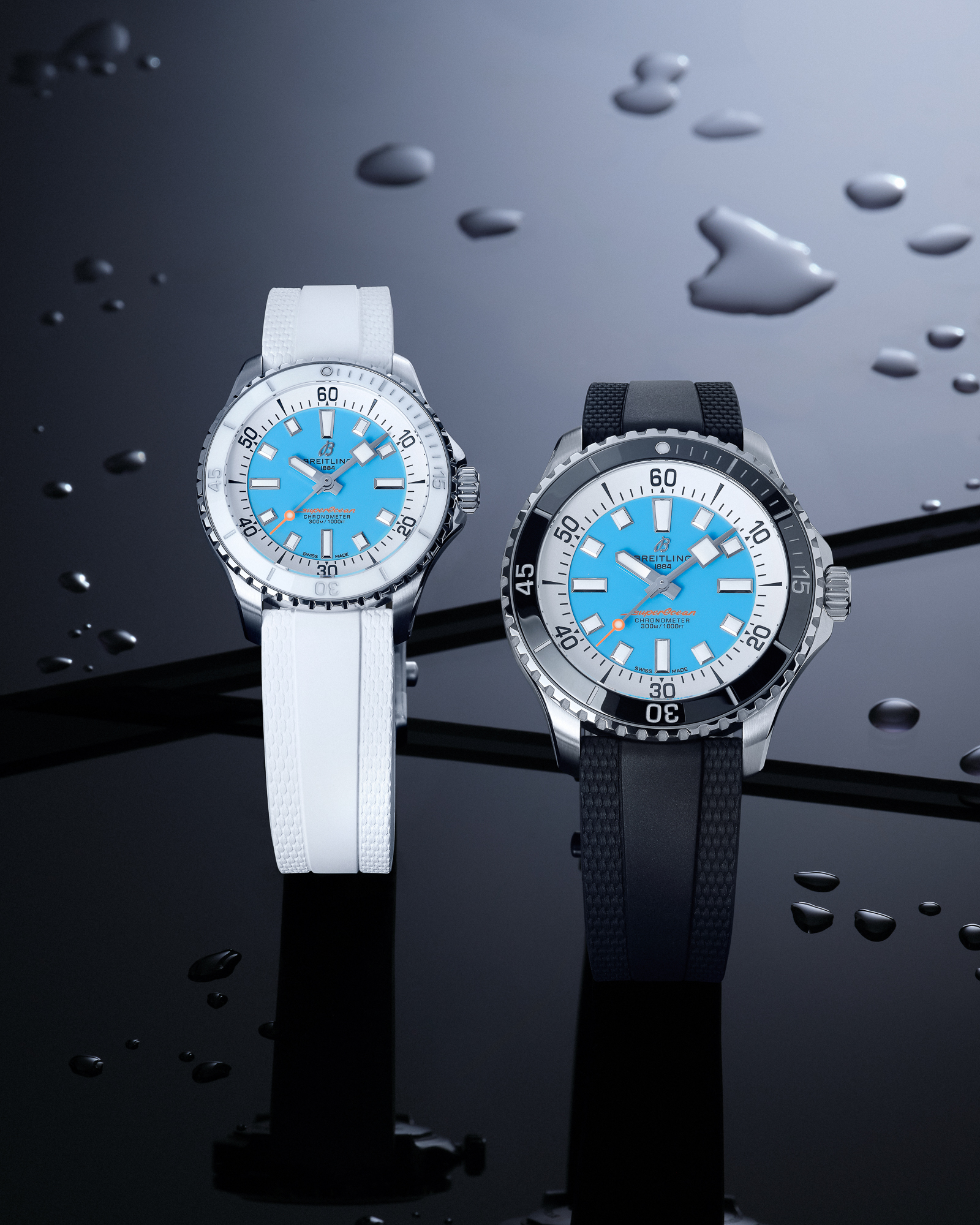 Two Breitling Superocean watches with light blue faces, one with a white band and one with a black band, on a wet black surface.