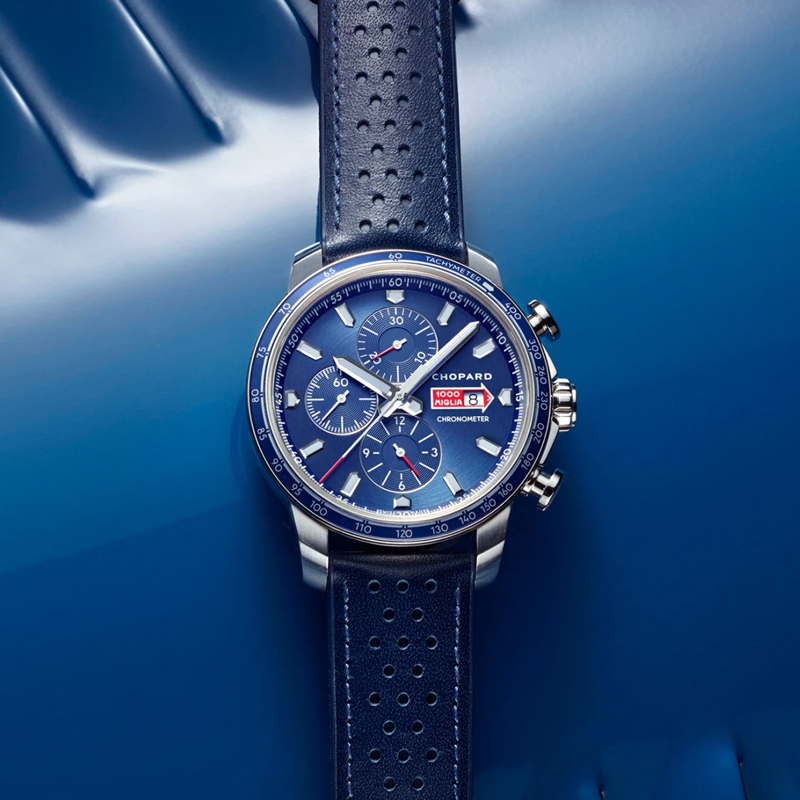 A Chopard Mille Miglia Chronometer watch with a blue dial, silver case, and perforated blue leather strap.