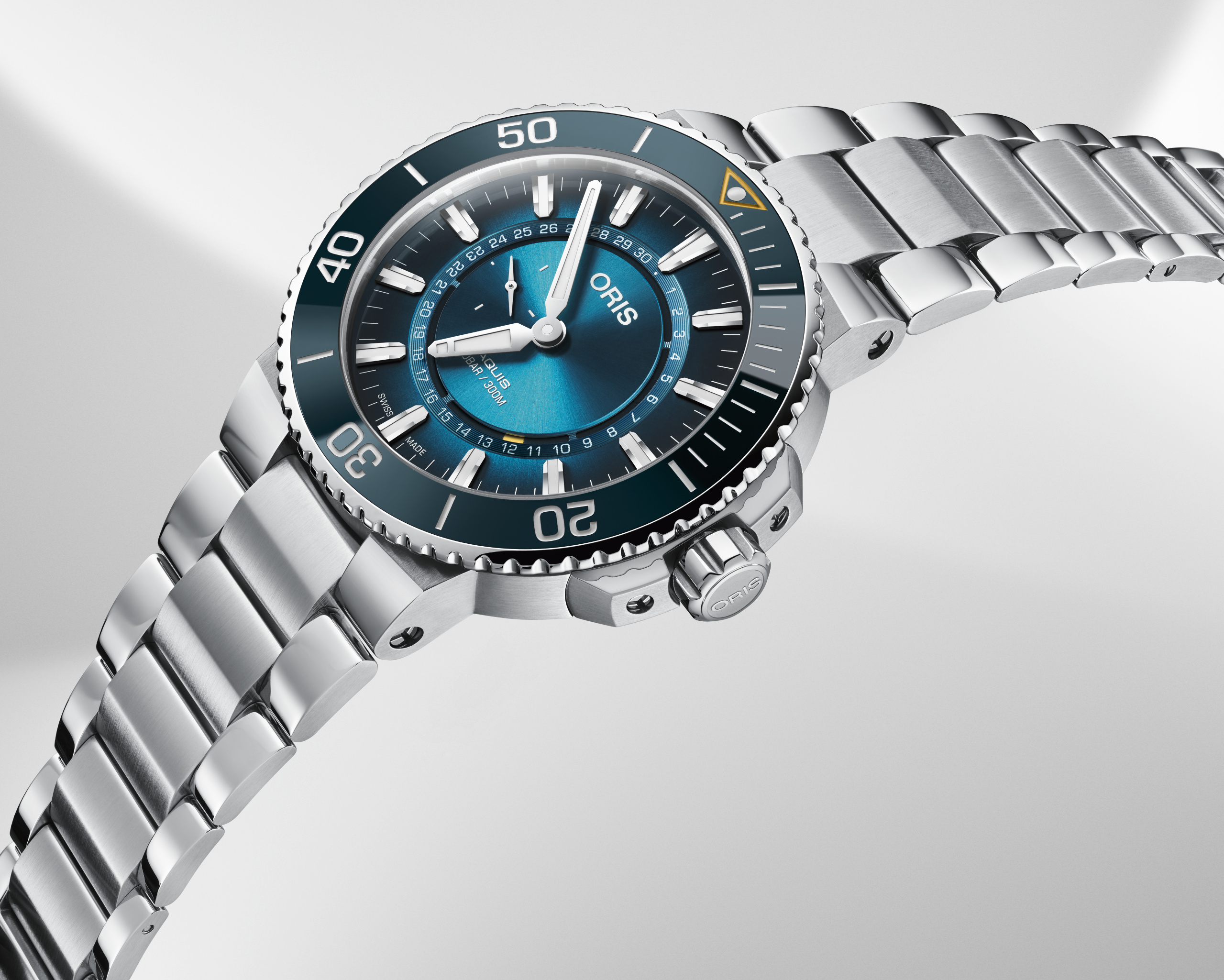 A silver dive watch with a teal face and bezel, featuring a metal link band.