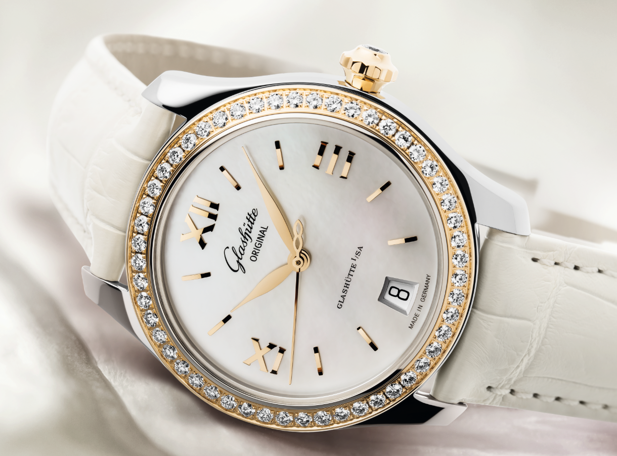 A Glashütte Original women's watch with a white mother-of-pearl dial, diamond-set bezel, and white alligator strap.