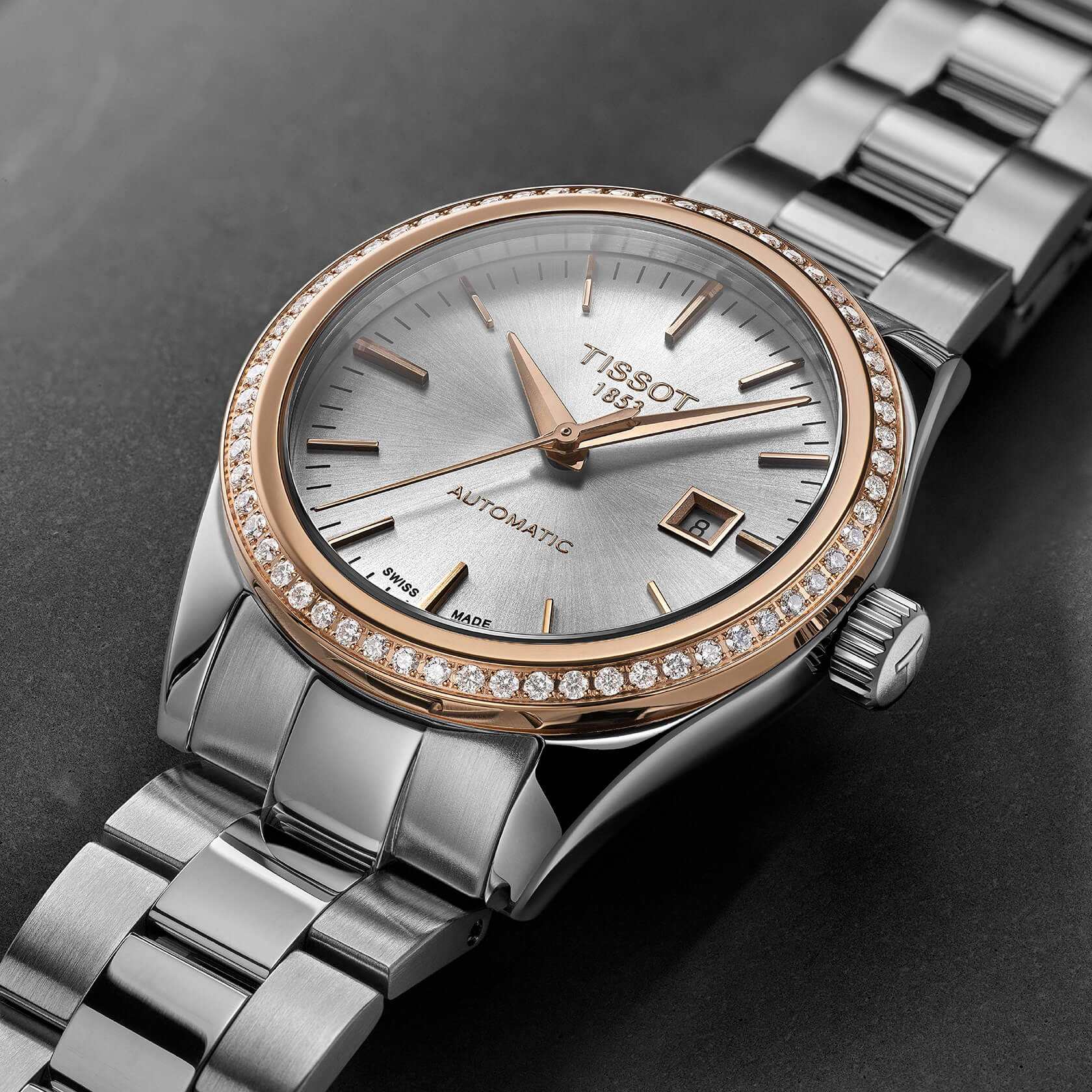 Montre automatique Tissot en argent et or rose avec lunette sertie de diamants et guichet de date.