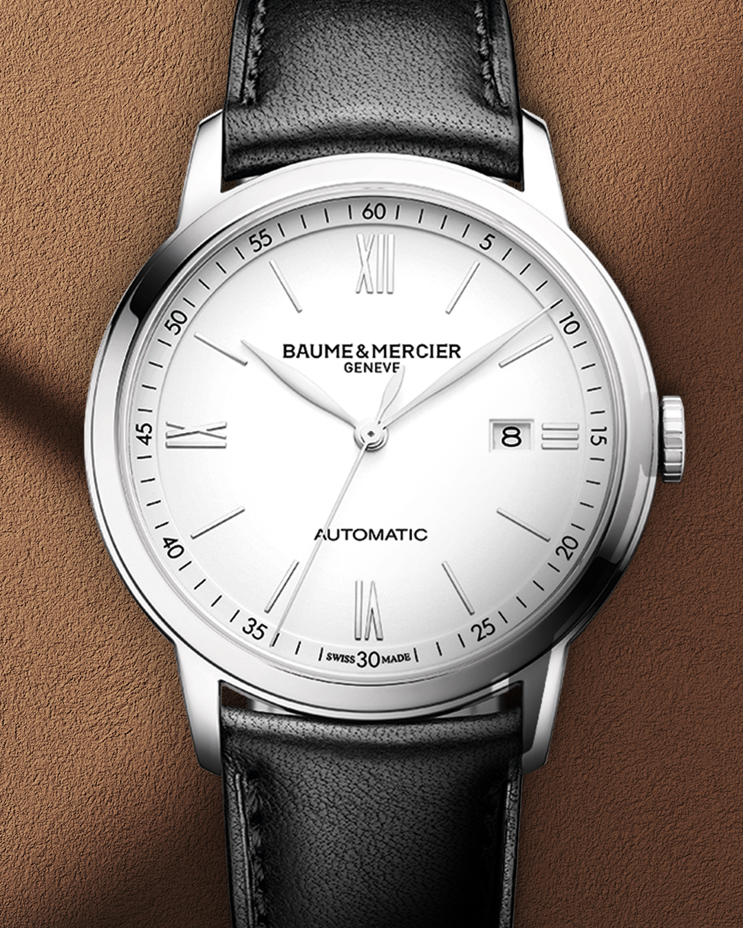 A silver Baume & Mercier automatic watch with a white face, black leather strap, and date display.